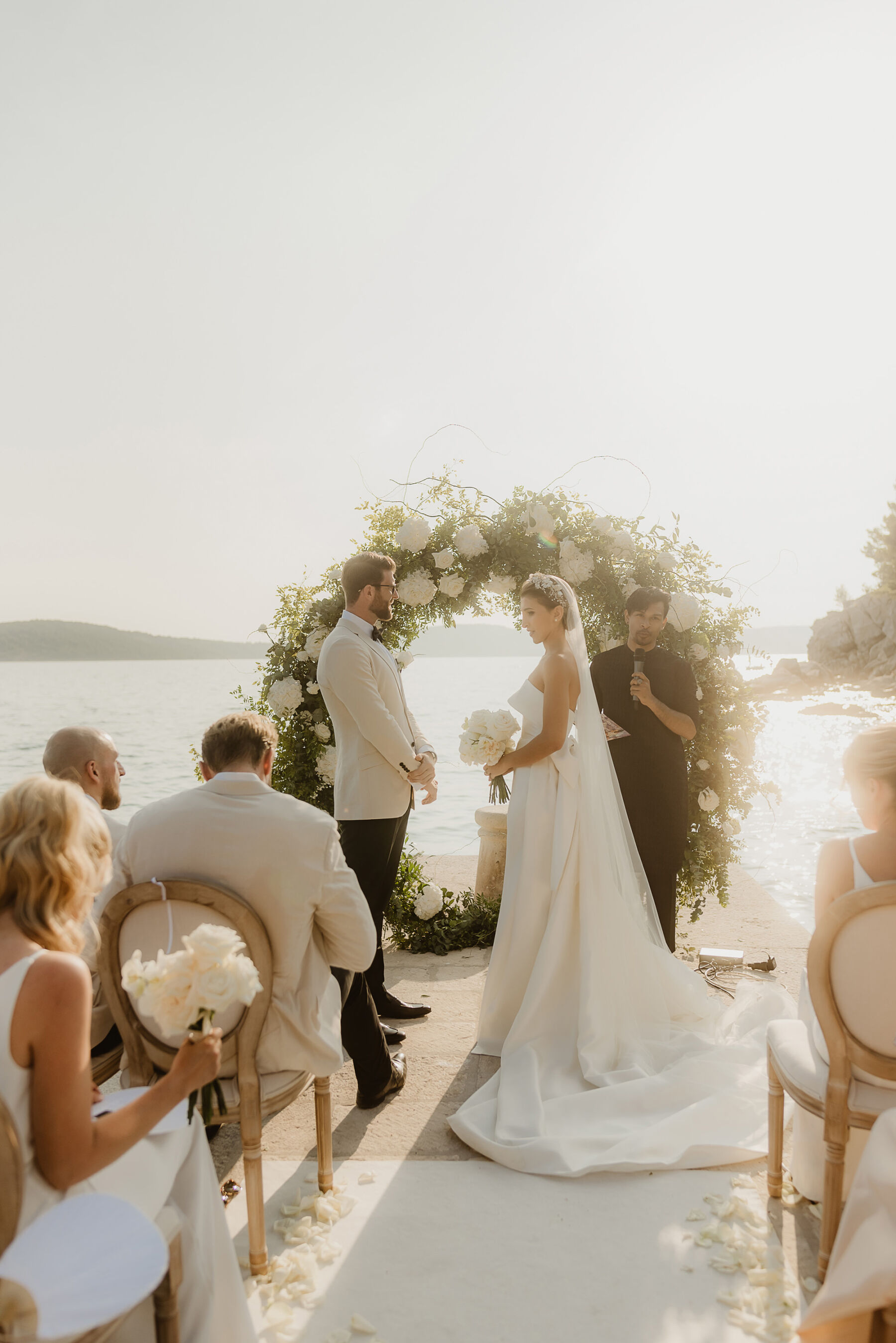 Floral arch backdrop for outdoor wedding ceremony by the sea