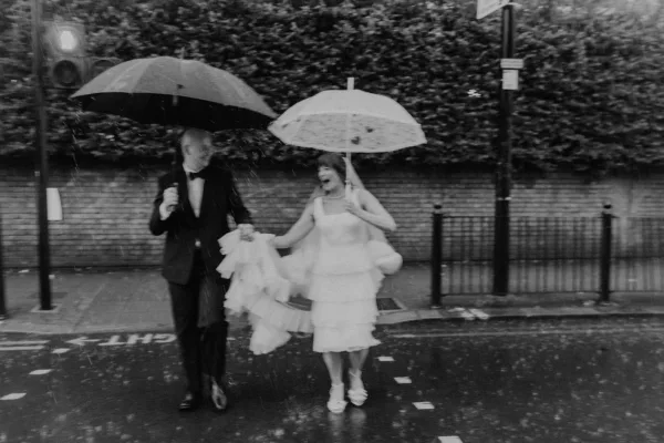 bride groom crossing road in pouring rain in Hackney