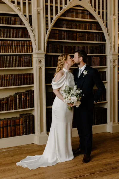 Bride & Groom kiss whilst stood in the Library at Strawberry Hill House. The bride holds her bouquet of green and white flowers.