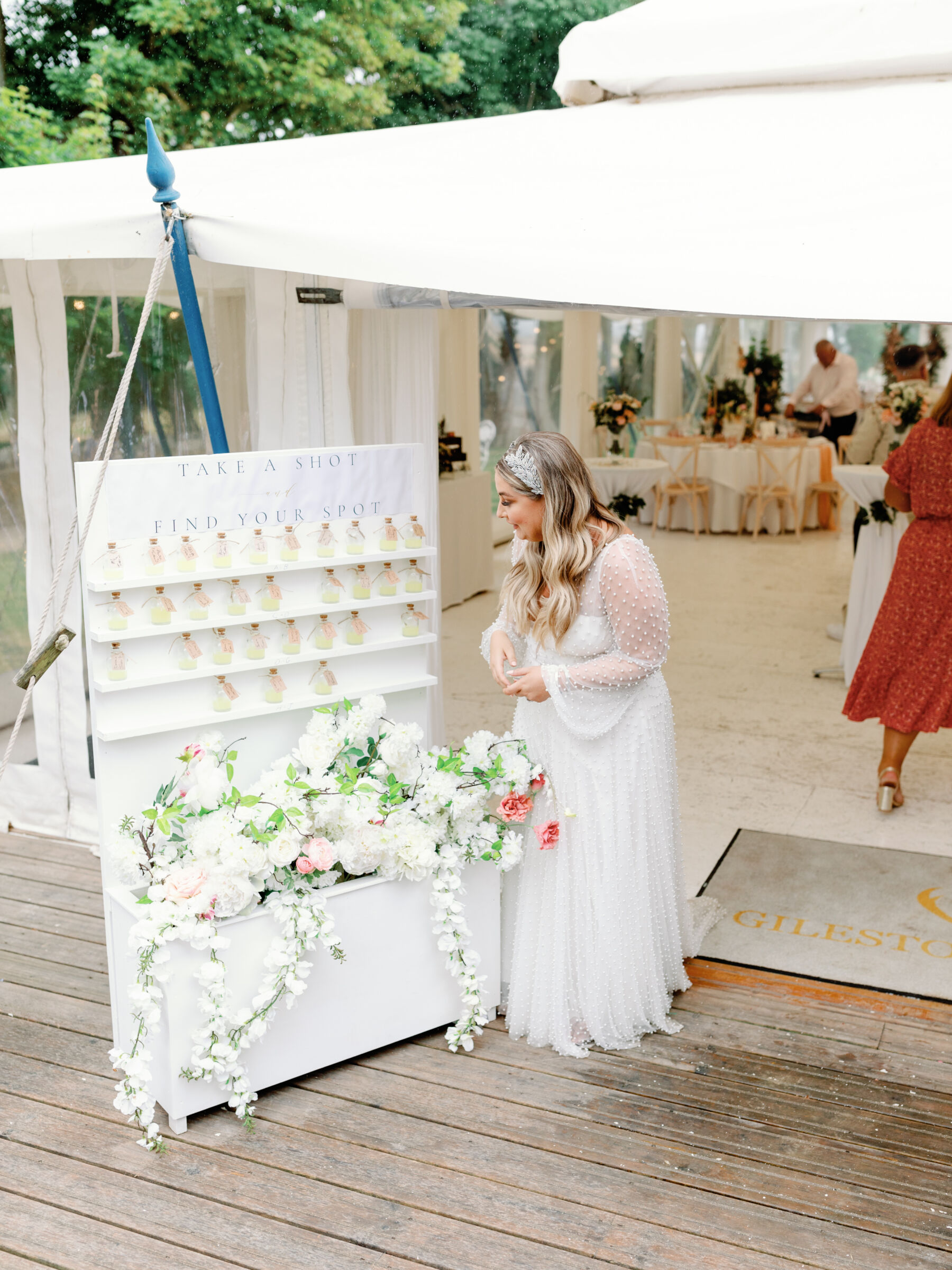 Bride i a pearl dress looking at the take a shot, find your spot table plan