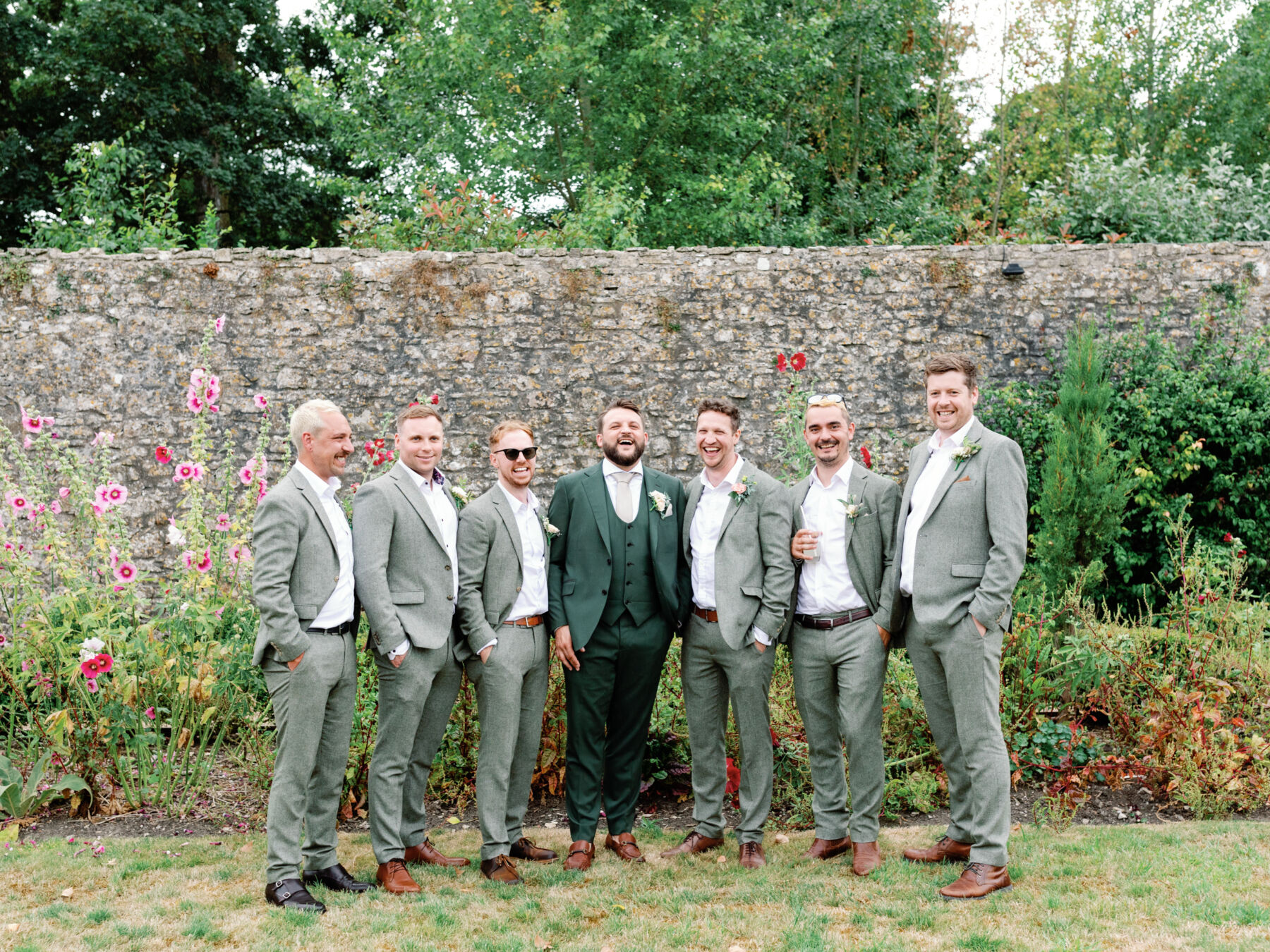 Groom in a green 3 piece suit and his groomsmen in pale grey suits.