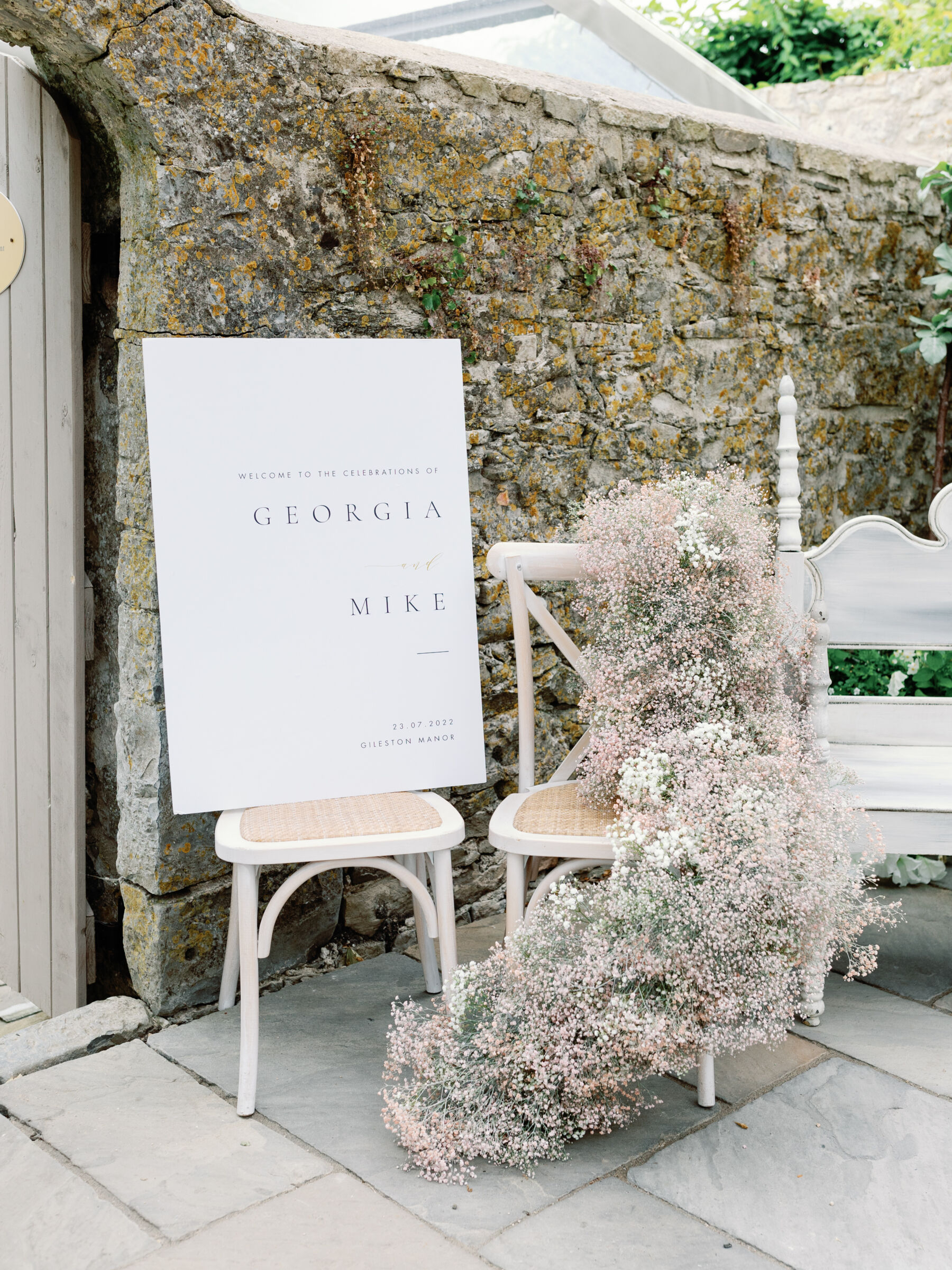Wedding welcome sign and white cross back wedding chair with cascading gypsophila flowers