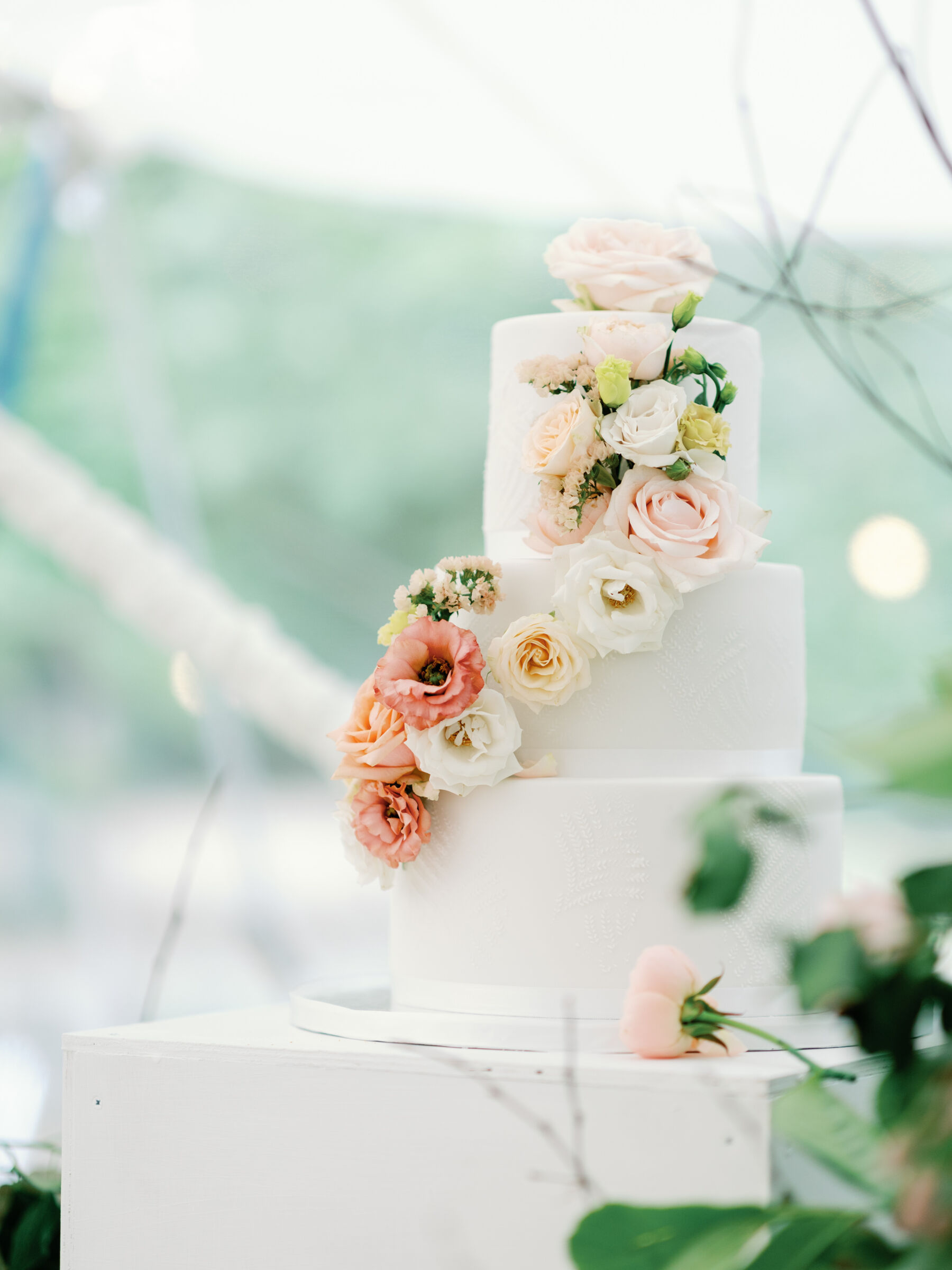 3 tier wedding cake with cascading peach and white flowers.