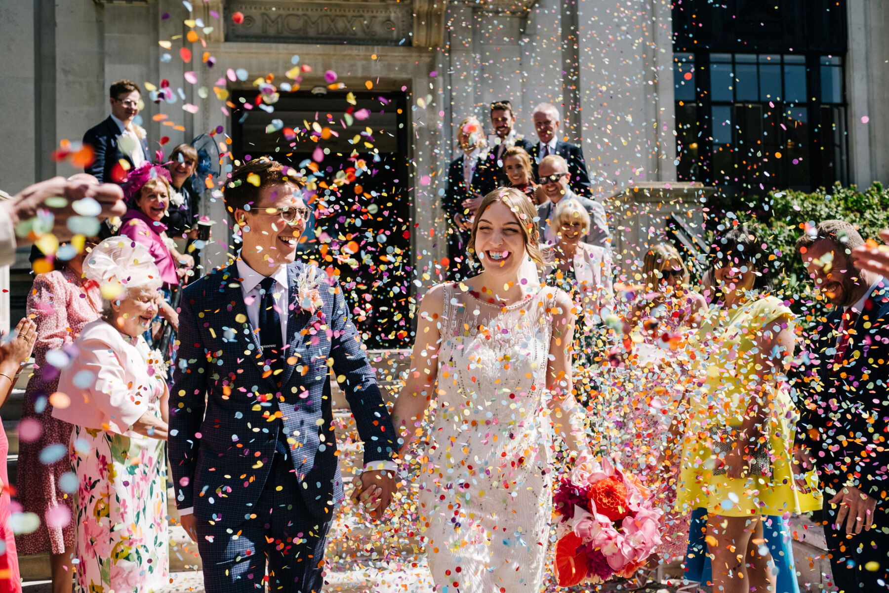 Colourful confetti showering down on a bride and groom on a sunny day