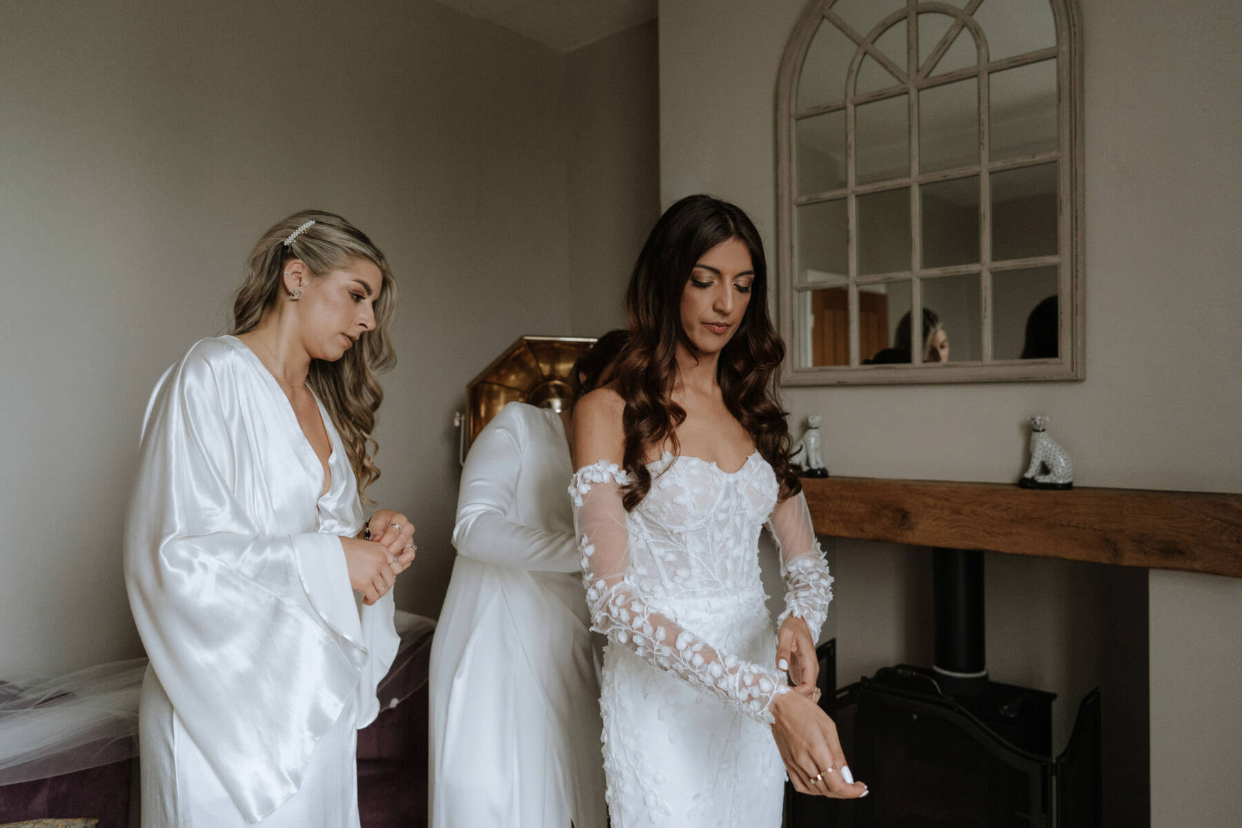 Bride getting ready in her Hadi Lane fitted, floral wedding dress. Bridesmaids in white dresses.
