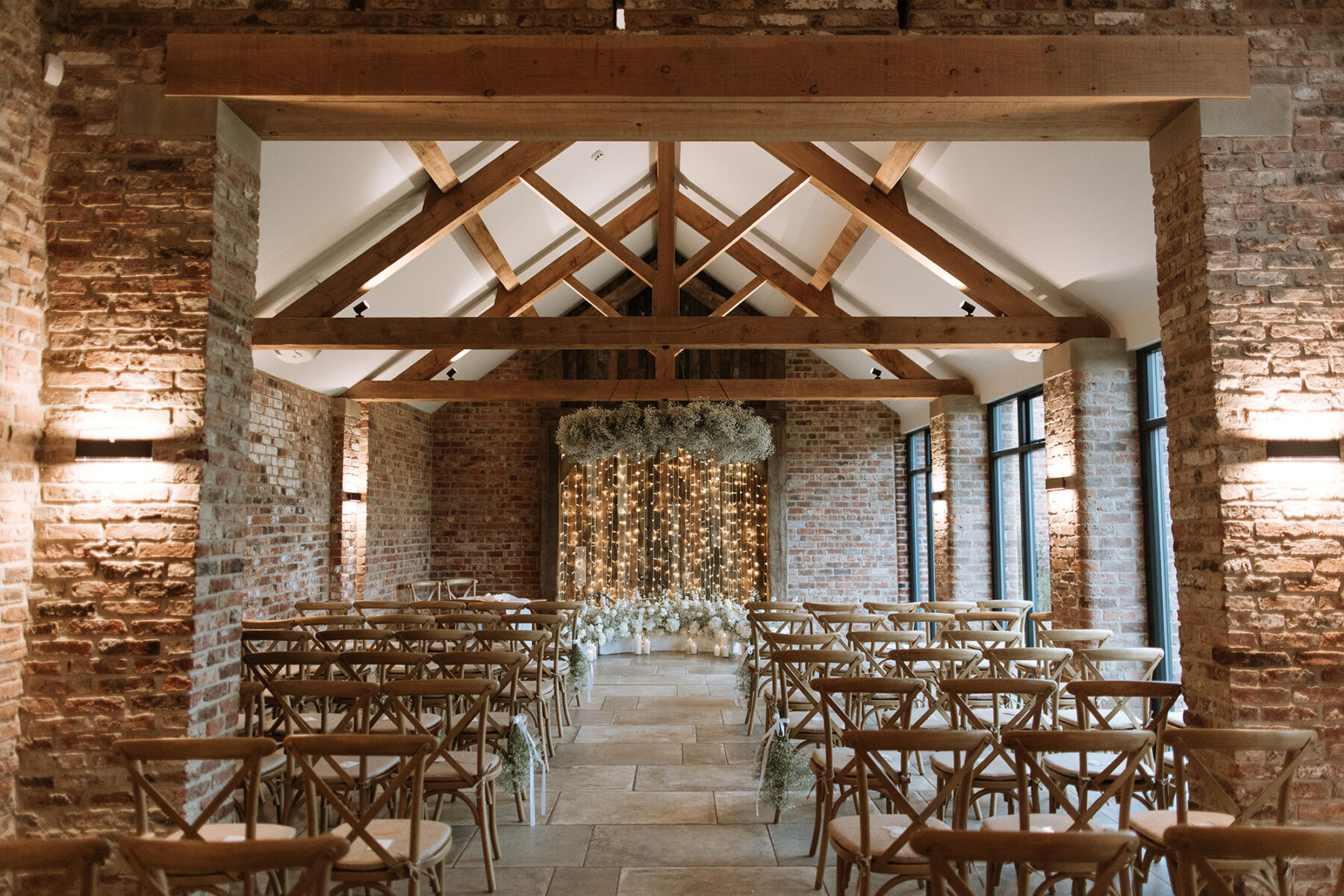 Thirsk Lodge Barns wedding ceremony space with gypsophila hanging from the ceiling and tied to crossback chairs.