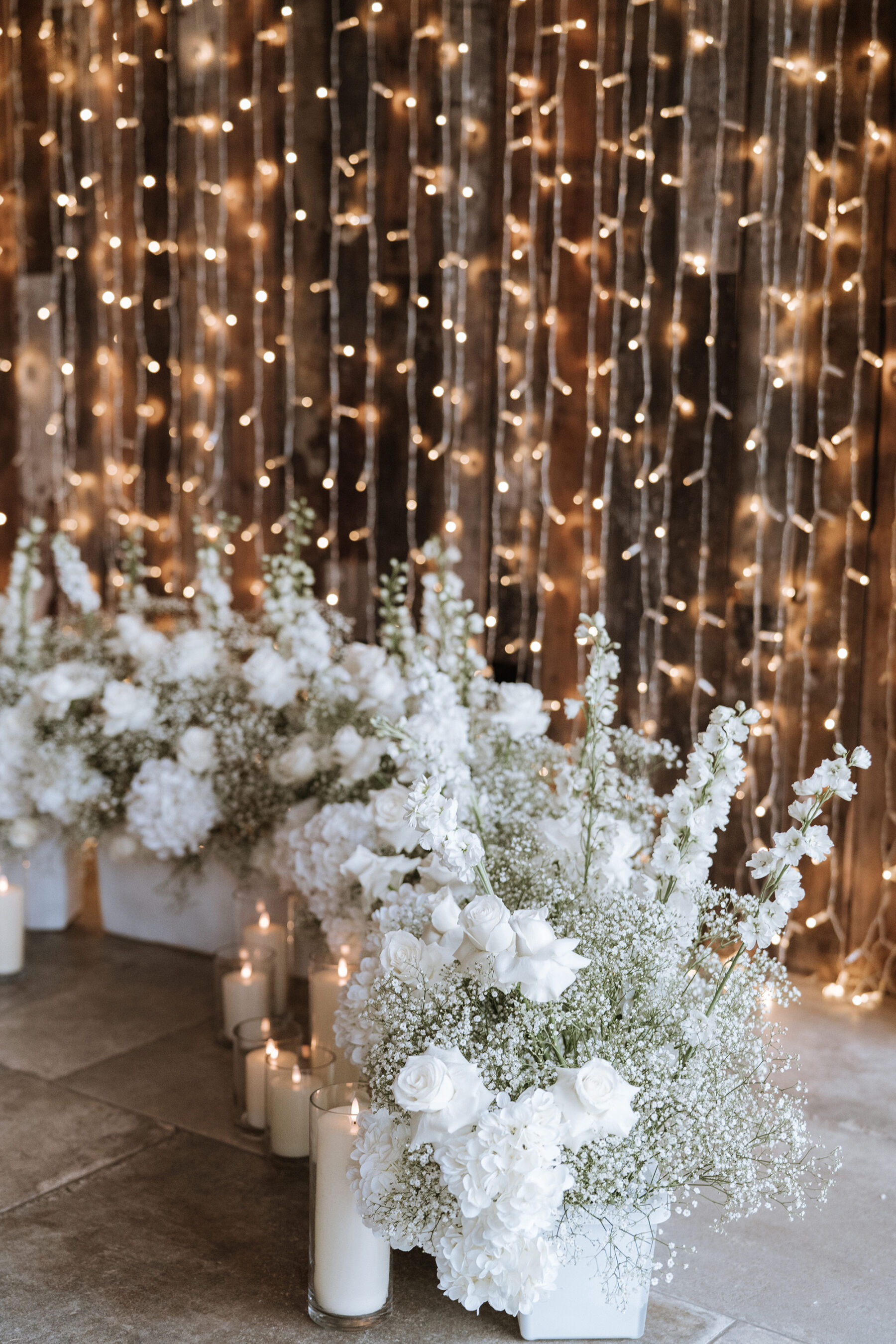 A Black Tie Wedding at Thirsk Lodge Barns for Serena in Madi Lane Bridal 16 All white wedding flowers positioned in small white ceramic trays on the floor.