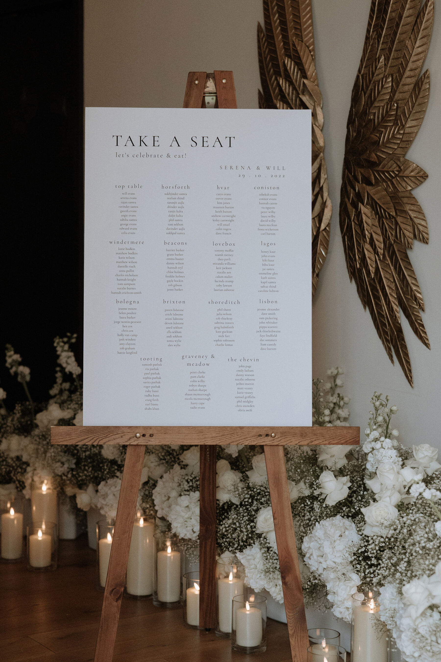 Take a seat wedding guest seating plan on a wooden easel.