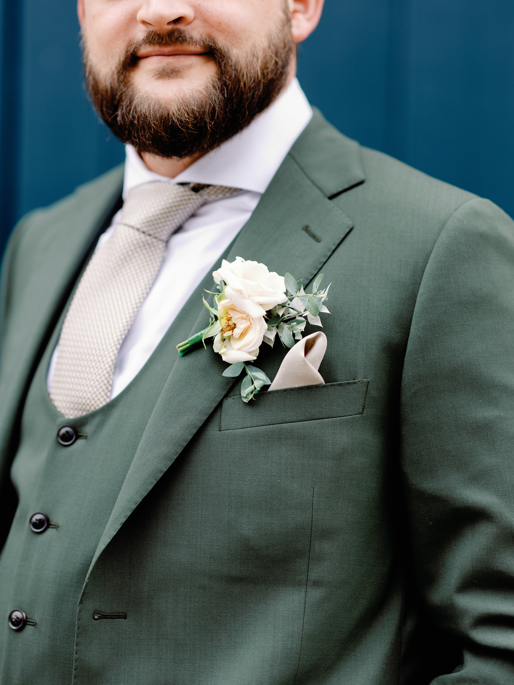 Groom in a green suit from Edit Suits with an elegant peach colour buttonhold.