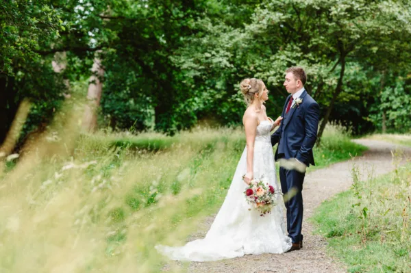 A bride & groom stand in the gardens surrounding Pembroke Lodge, Richmond Park. The Bride holds her bouquet by Myrtle & Smith Flowers.