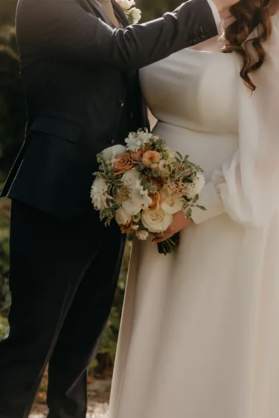A close up image of a bride holding her bouquet. Full of ivory and toffee colours flowers by Myrtle & Smith Flowers.