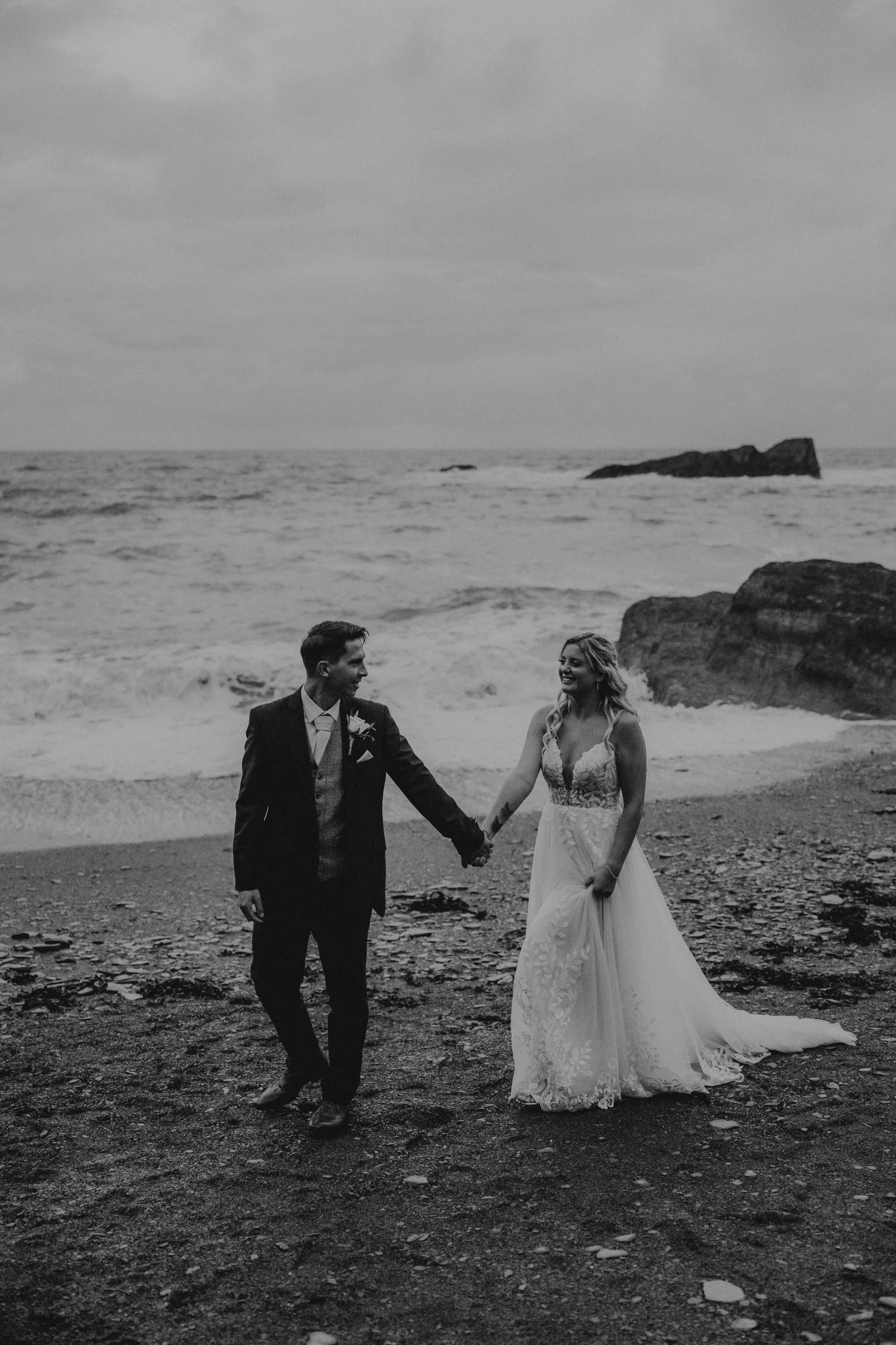 couple walking on the beach at tunnels ebaches weddign venue