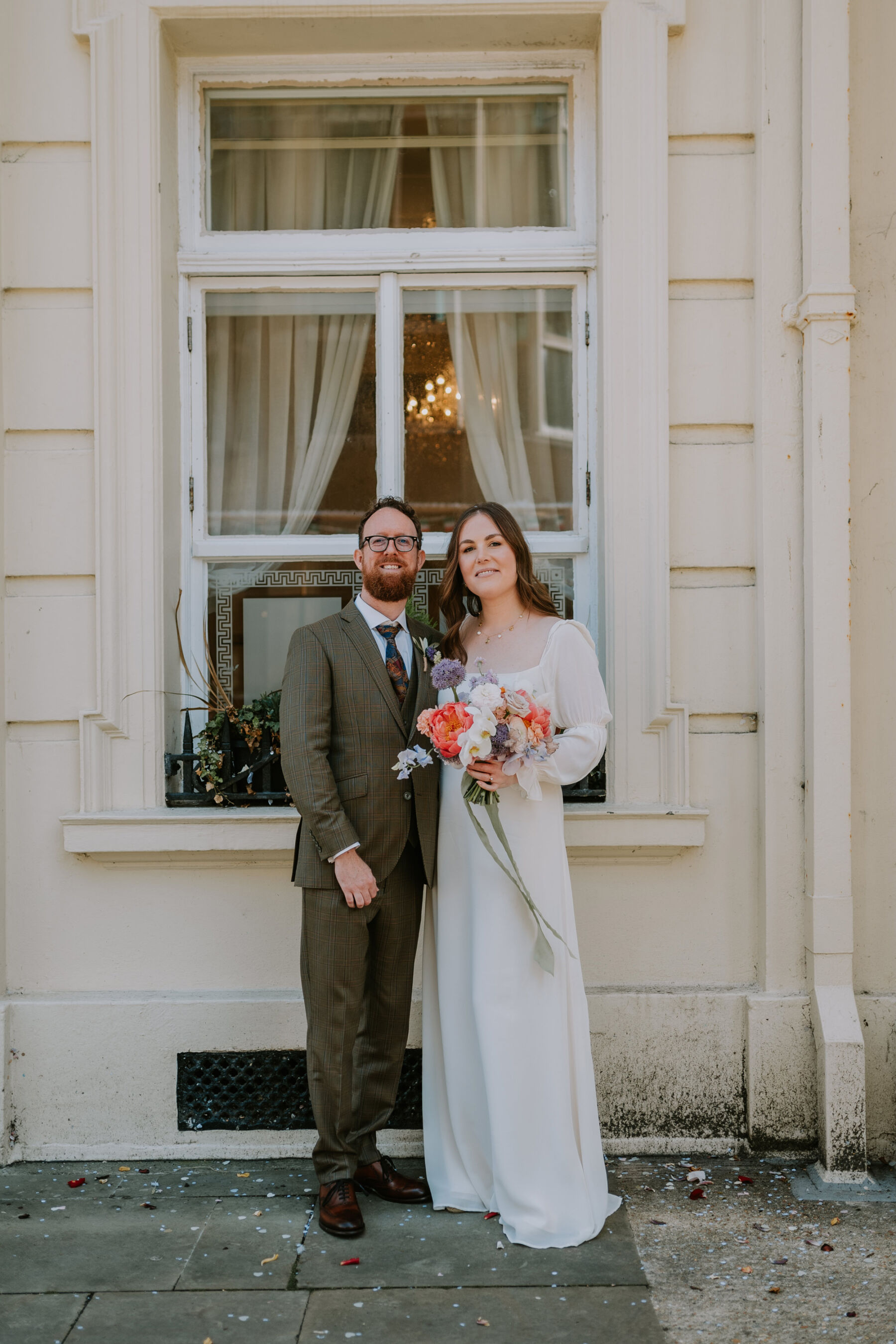 Bride wearing a Reformation wedding dress & carrying a colourful bouquet.