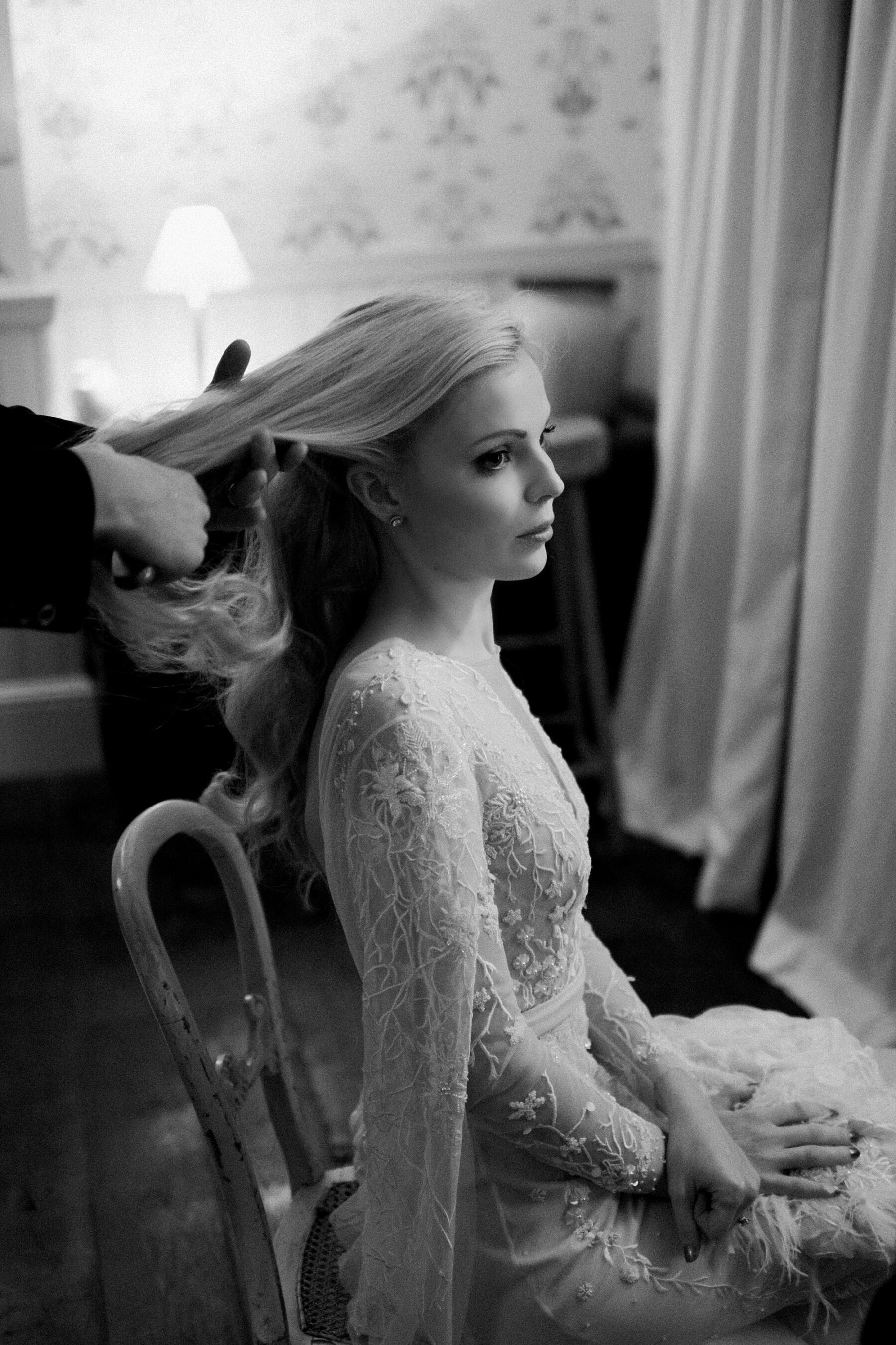 Black and white images of bride wearing Hermione de Paula wedding dress having her long blonde hair brushed, by Claudia Rose Carter Photography.
