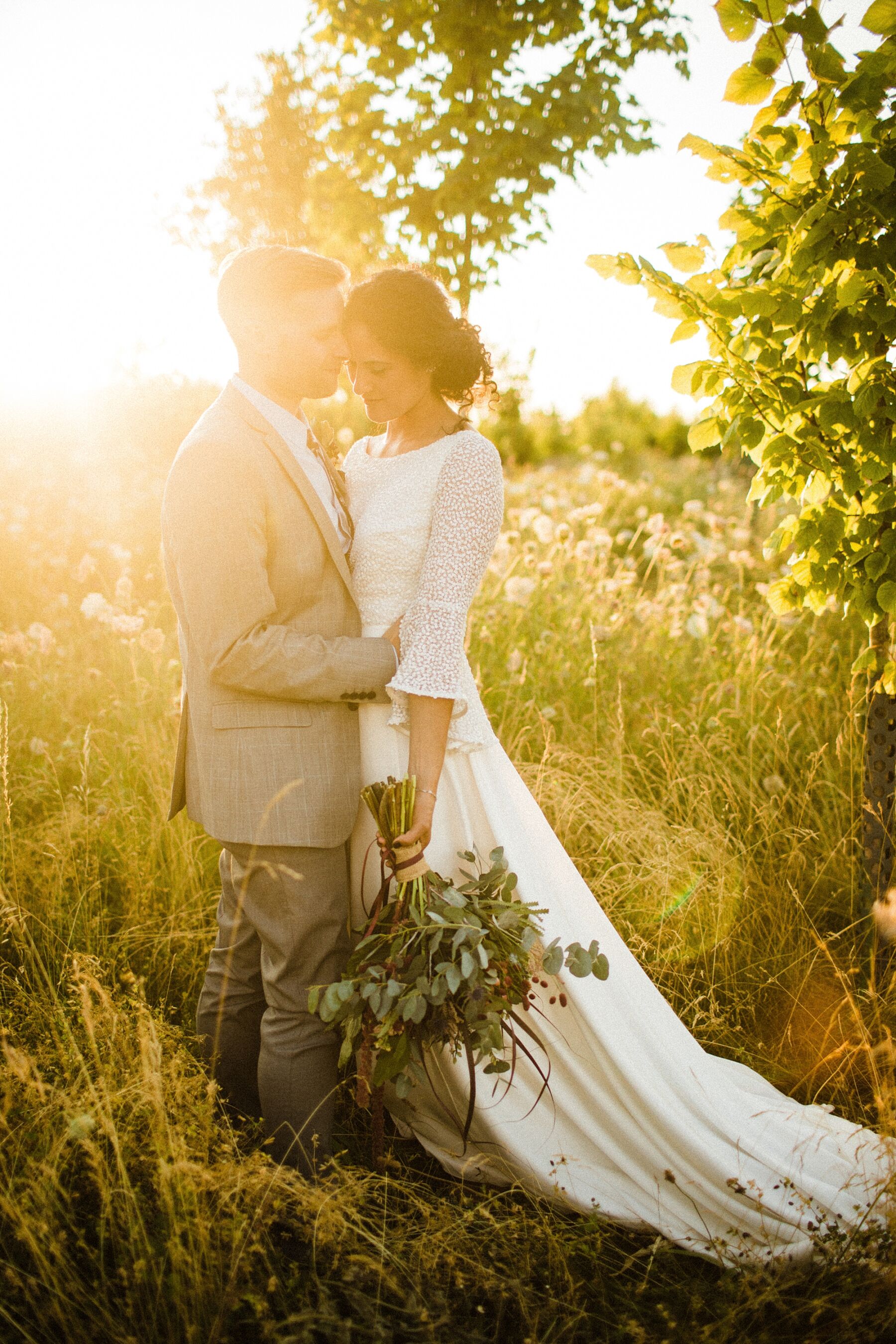 Golden hour shot of bride and groom hugging each other in a field, by Claudia Rose Carter Photography