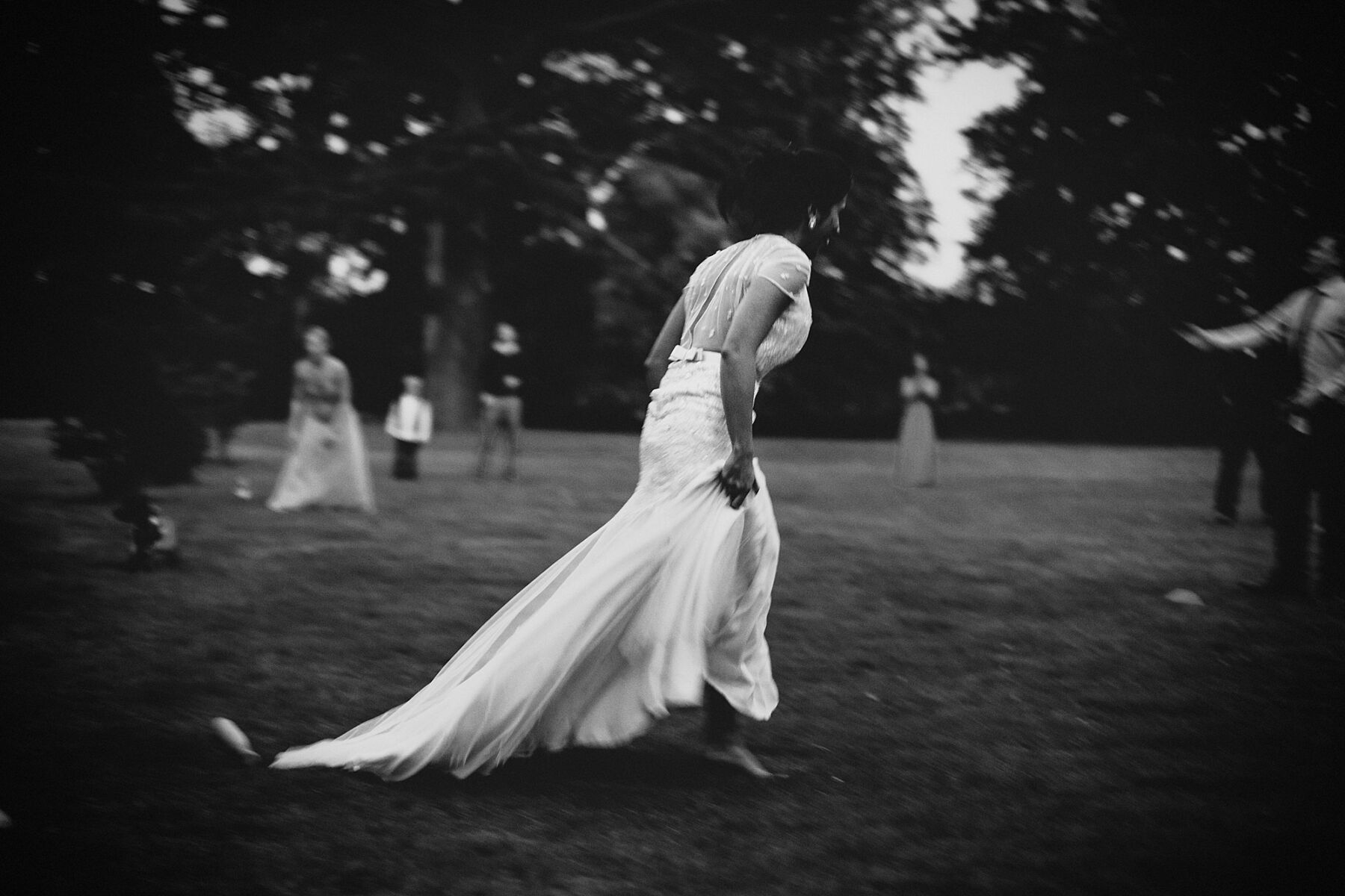 Blurred black and white images capturing bride running across a field, by Claudia Rose Carter Photography.