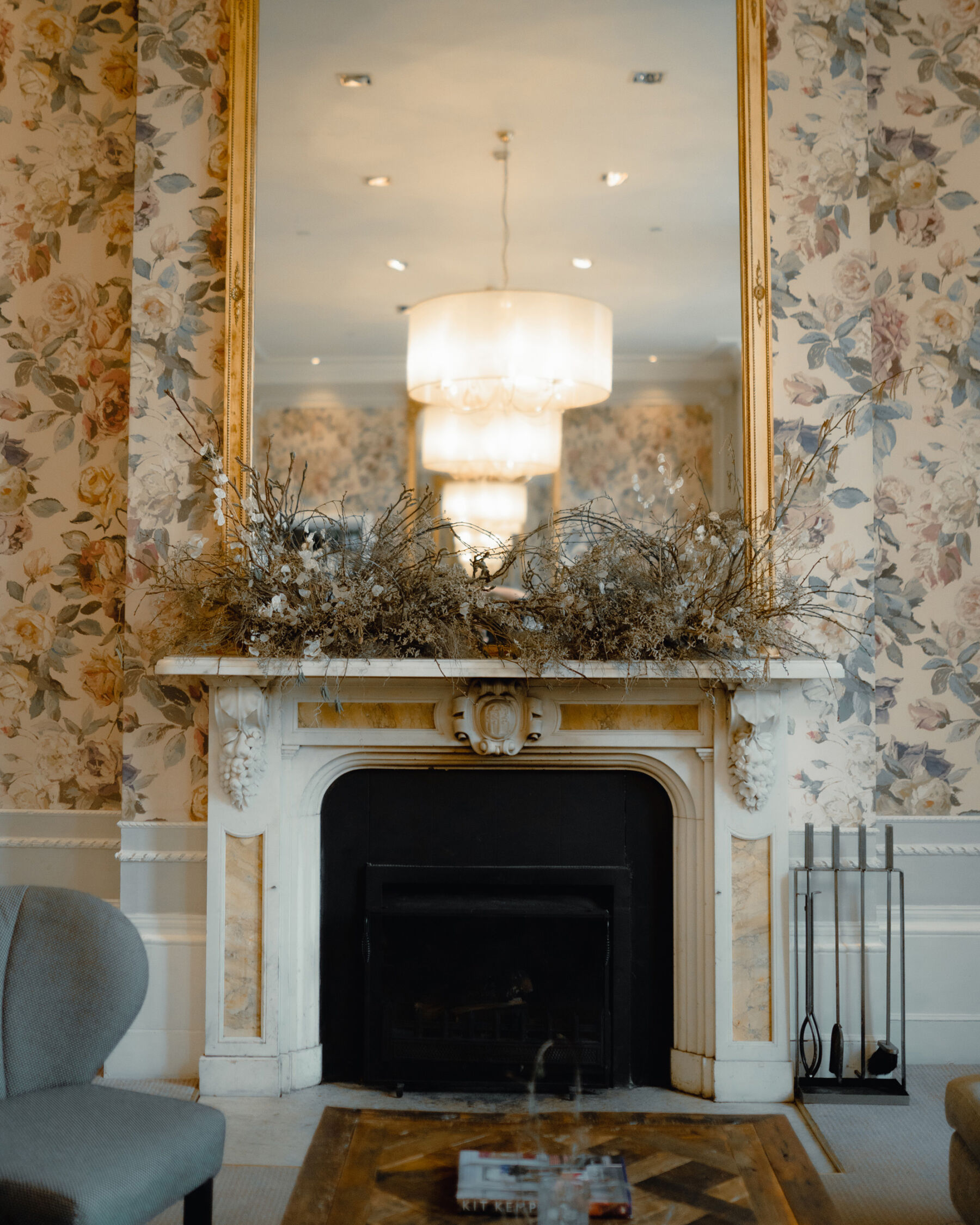 Hampton Manor fireplace with tall gold gilt edged mirror and dried flowers on the mantelpiece. 