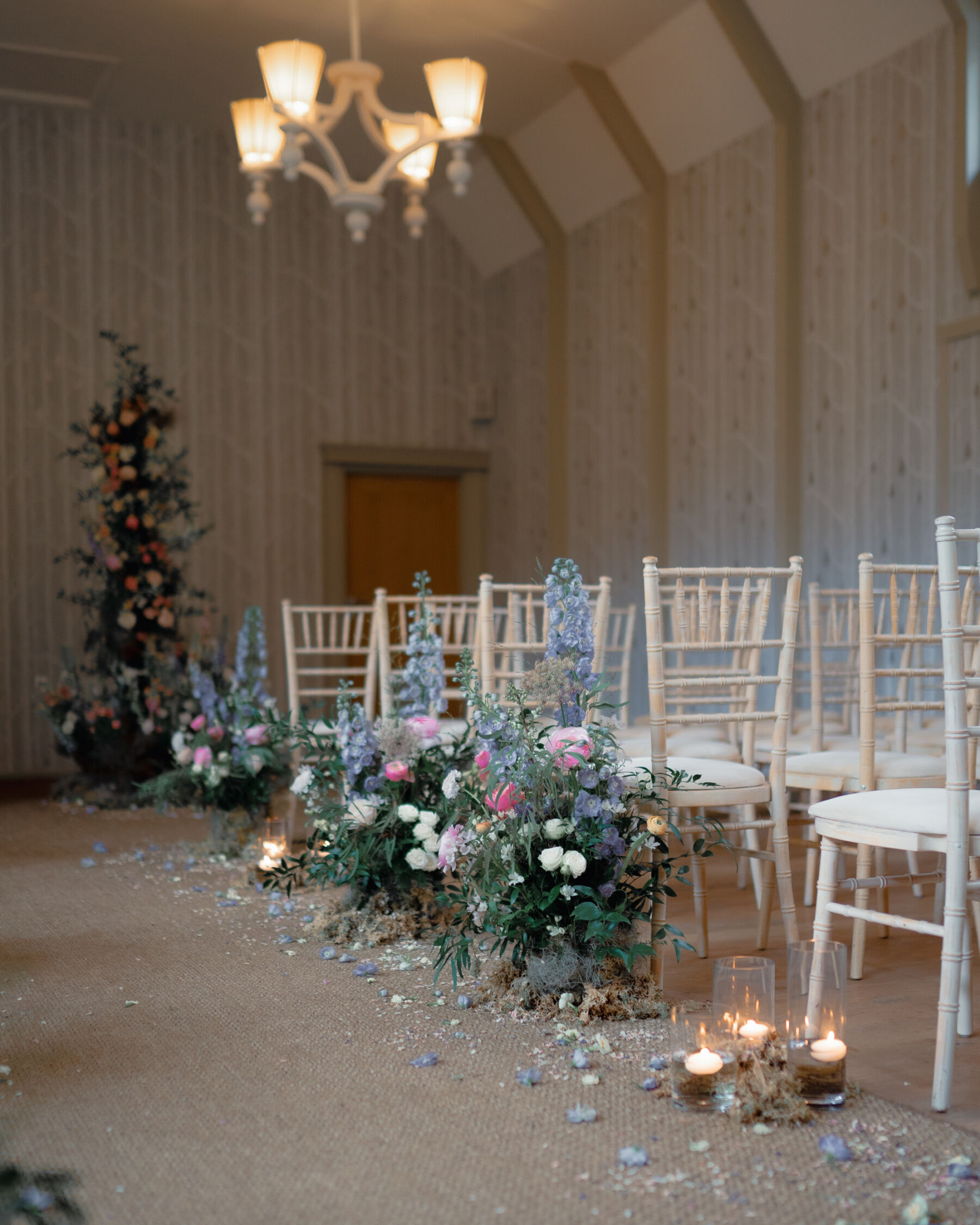 Wedding ceremony aisle lined with pastel flowers and scattered petals at Hampton Manor.