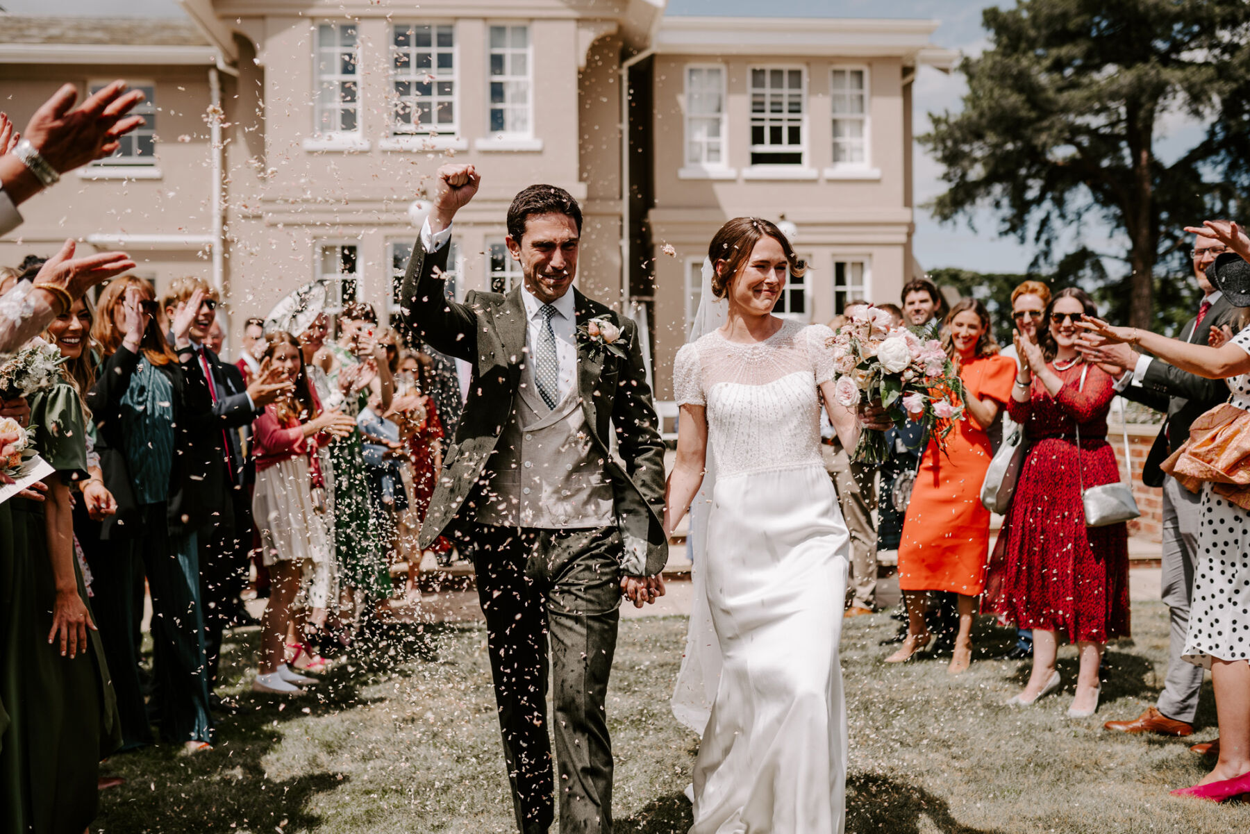 Bride wearing a Jenny Packham dress exiting her ceremony under a shower of confetti