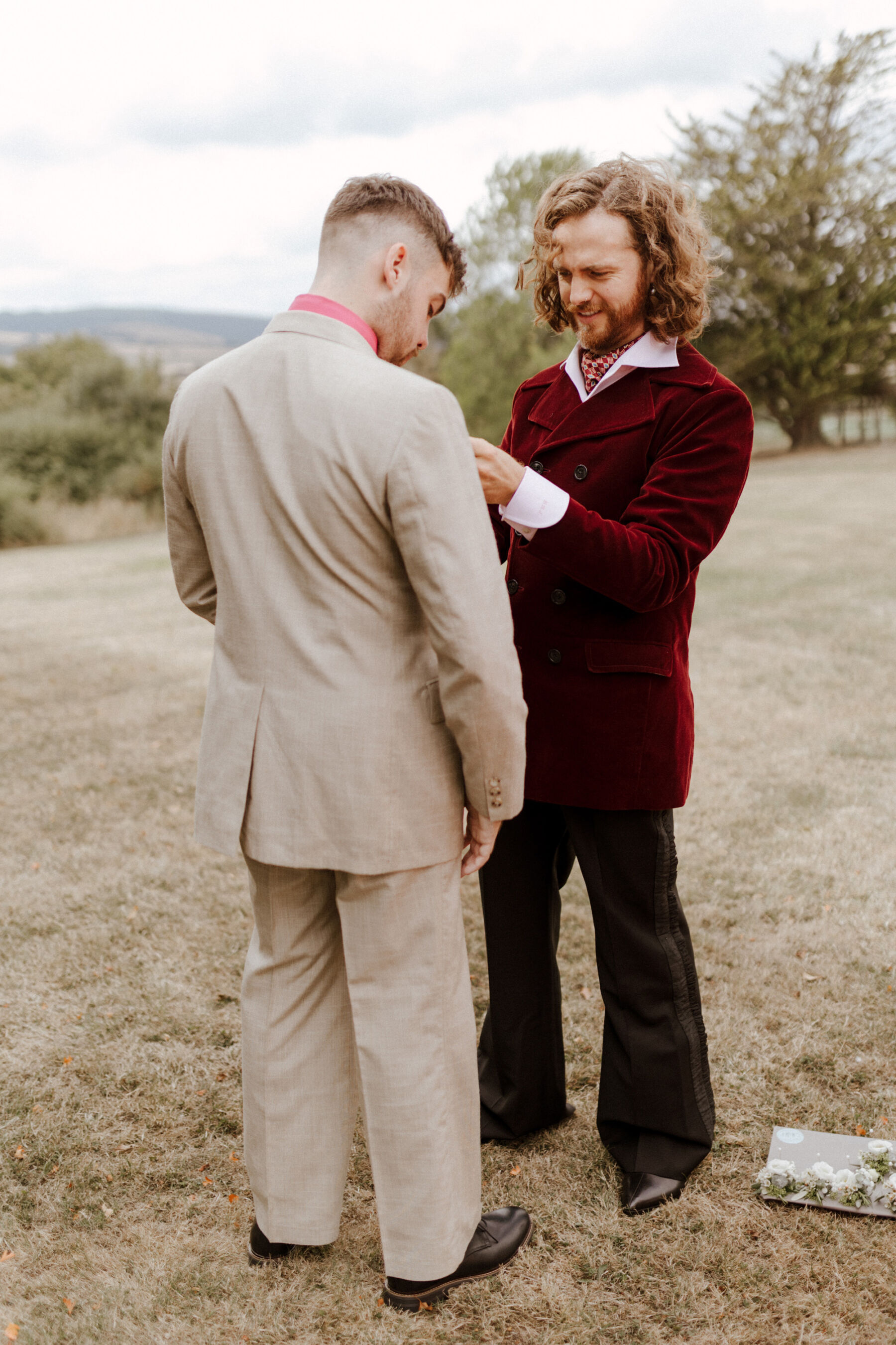 Groom in flared trousers and maroon red velvet suit.