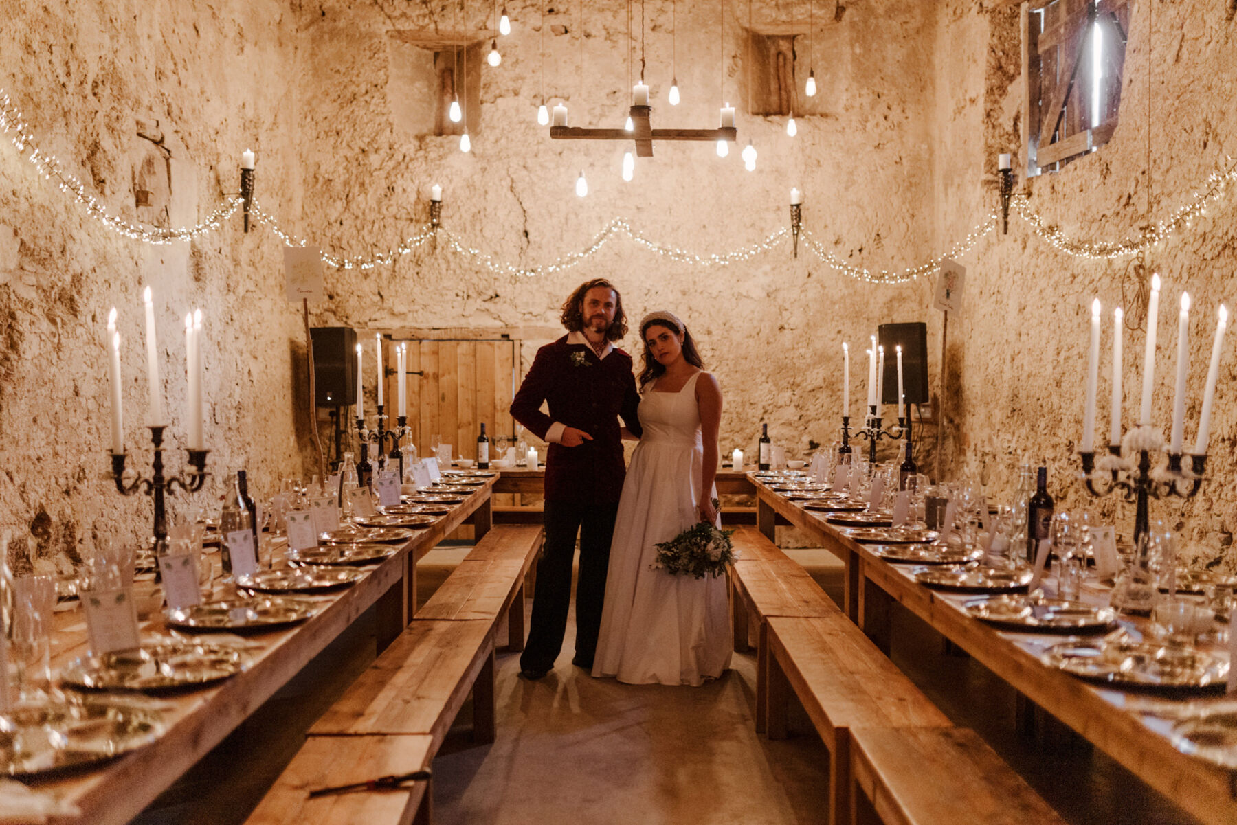 The barn at Higher Eggbeer farm, decorated with taper candles and surrounded by fairy lights for a wedding reception.