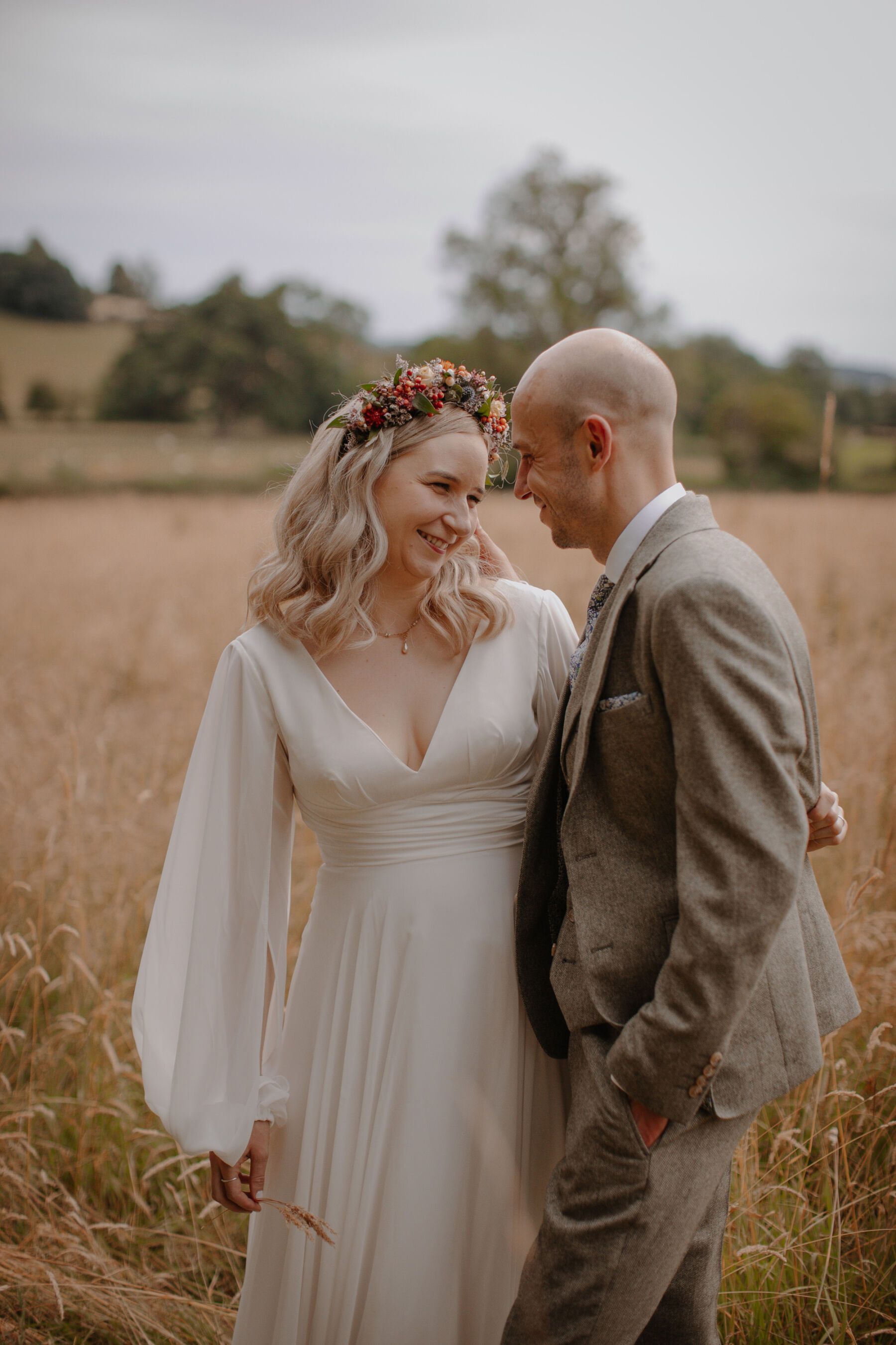 Bride and groom standing in a field.