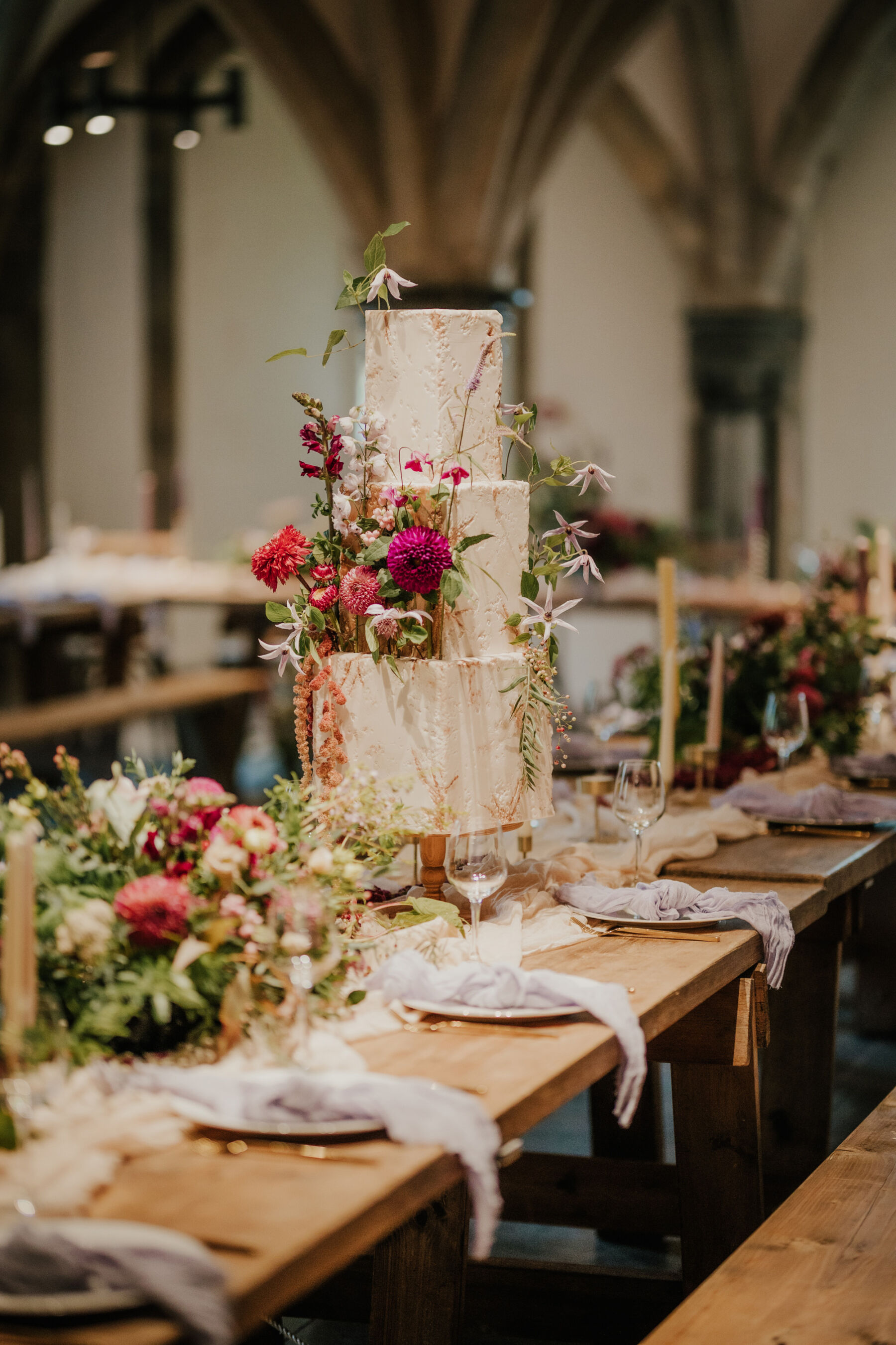Romantic and magical wedding cake with summer flowers and greenery. Bishop's Palace historic wedding venue in Wells, Somerset.