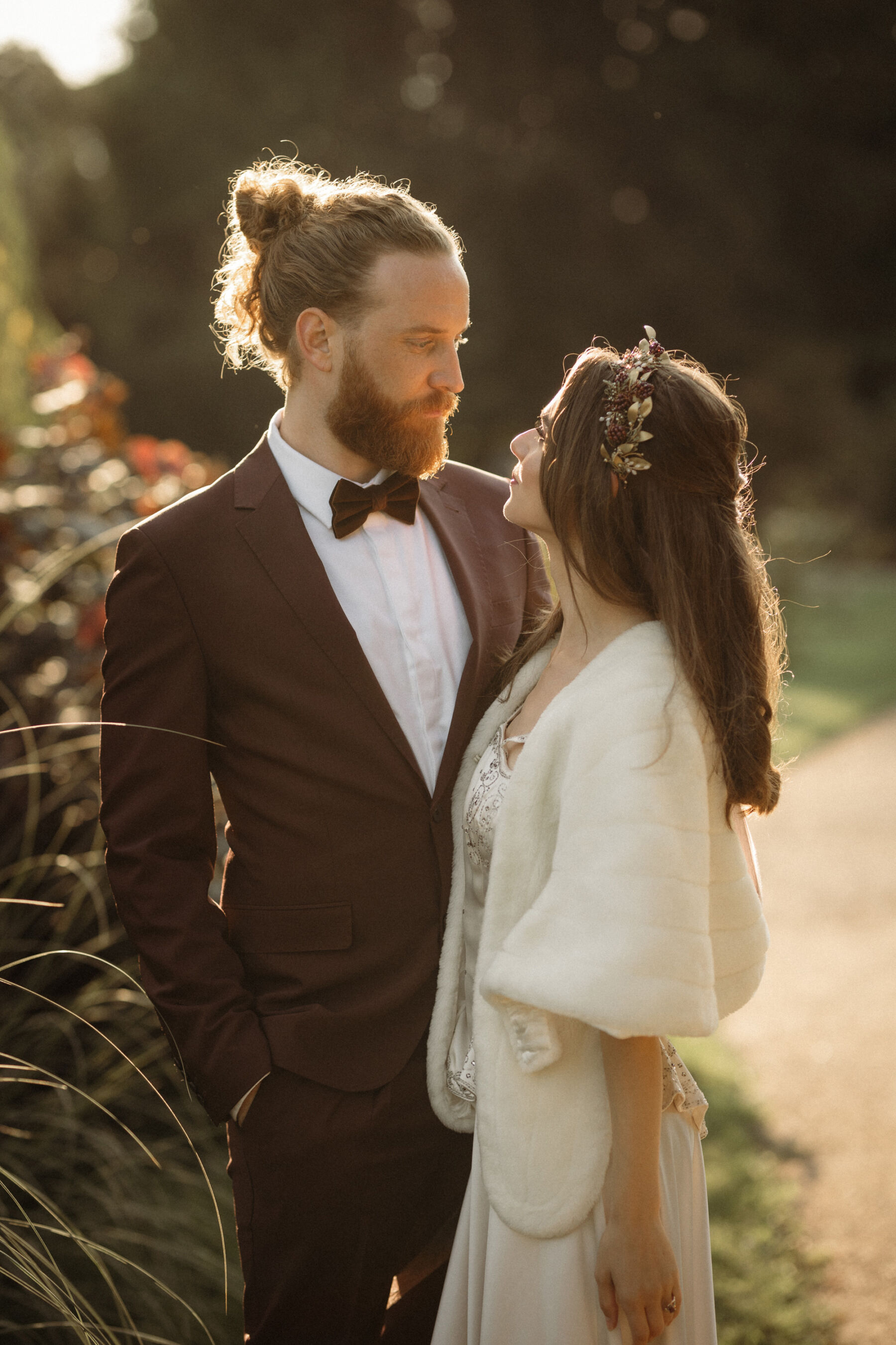 Bride in vintage dress, groom with a hair bun, bow tie and brown suit