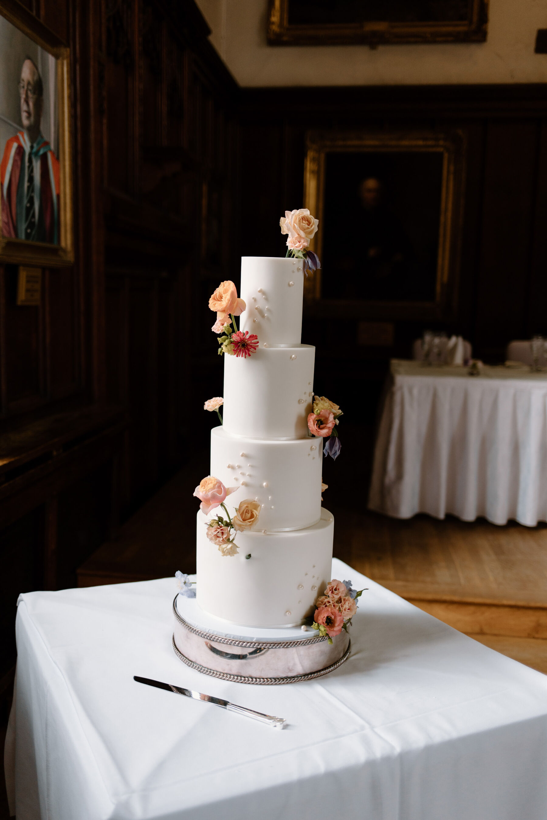 Livia in a Truvelle Bridal Gown for her Durham Castle Wedding With an Outdoor Summer Garden Ceremony 28 4 tier white wedding cake decorated with fresh flowers.