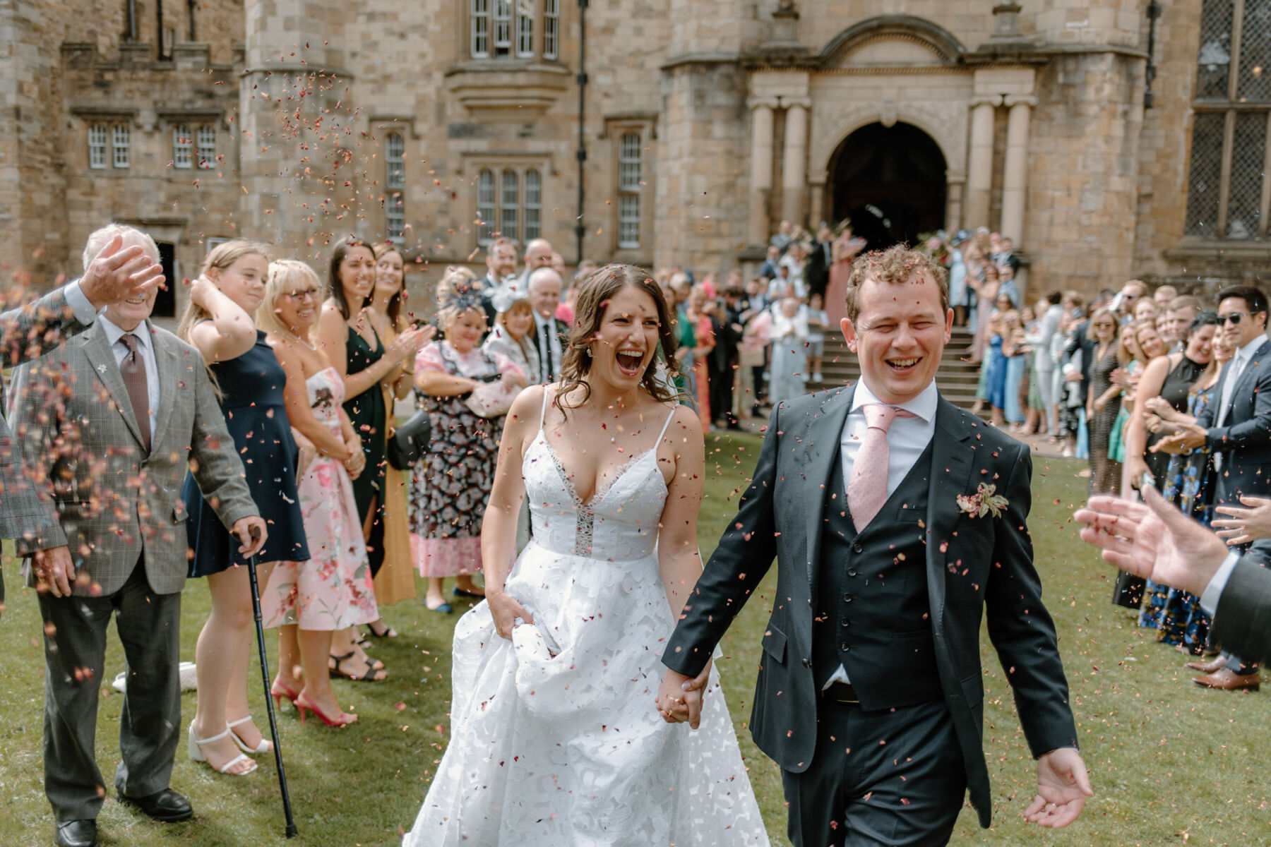 Confetti shot as bride in a Truvelle dress and Groom in a pink tie exit their church ceremony at Durham Castle. 