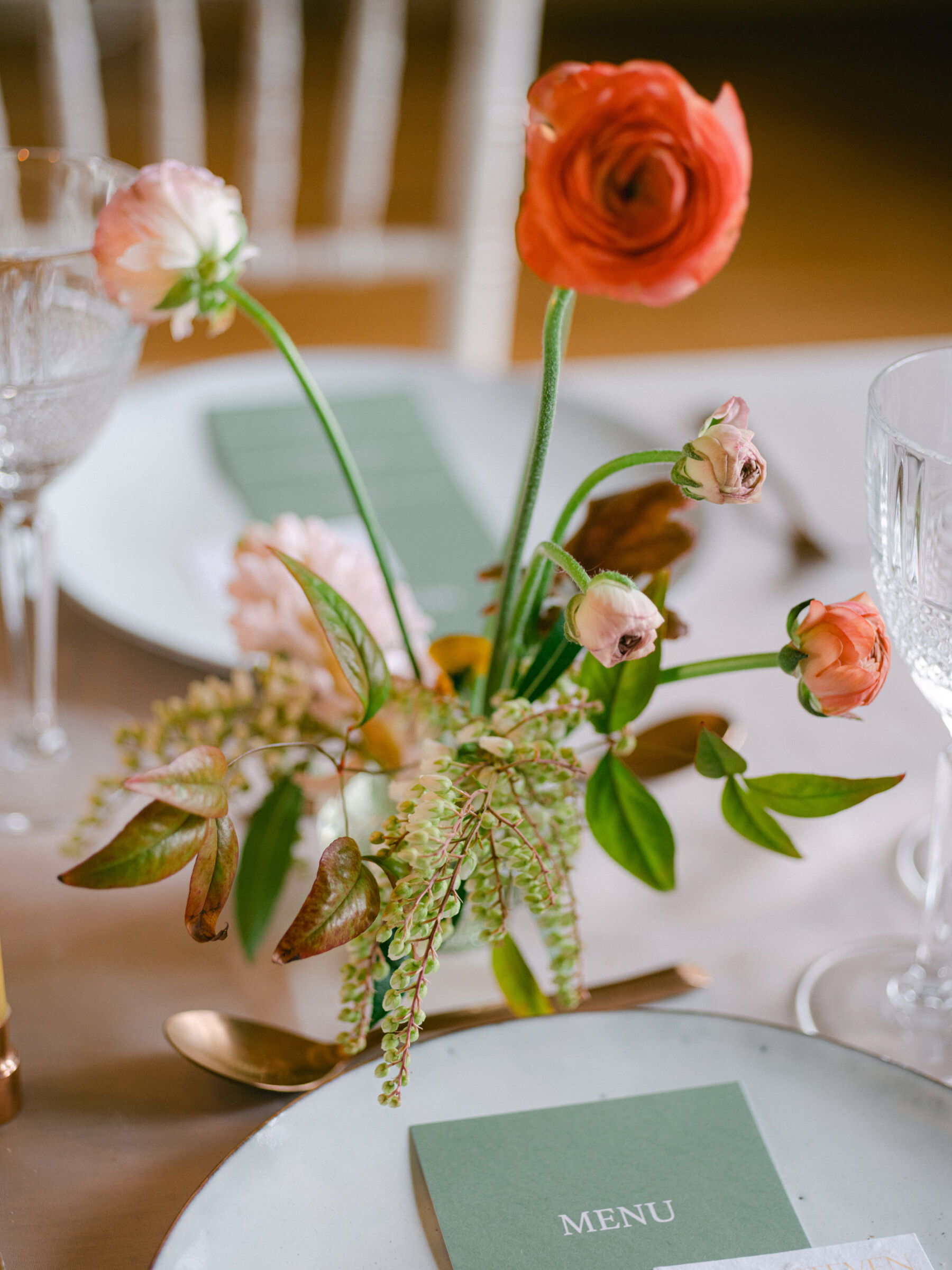 British grown Ranunculus in orange & other British grown wedding flowers in floral frogs. Elegant wedding table decor with copper cutlery. 