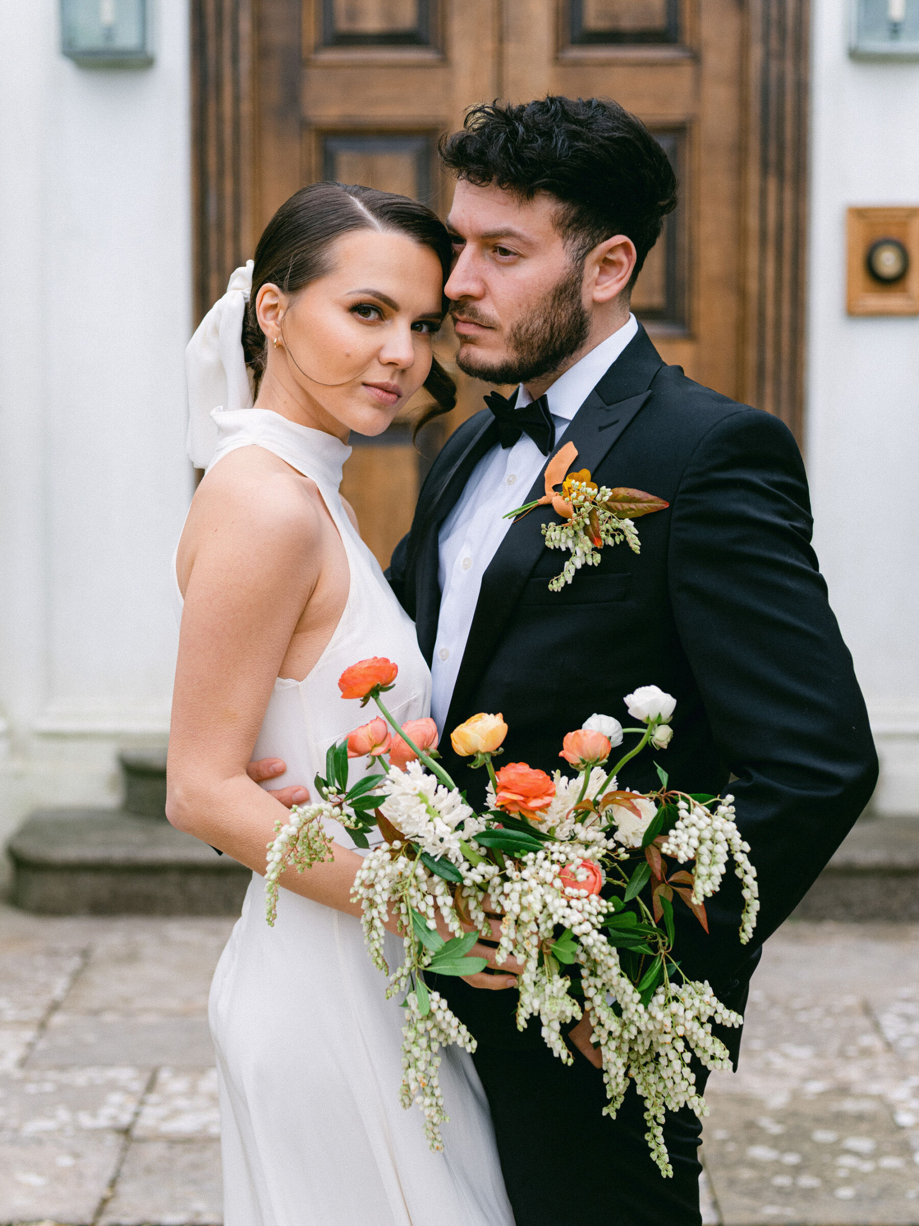 Bride in a halterneck wedding dress and carrying a colourful bouquet of British grown flowers.