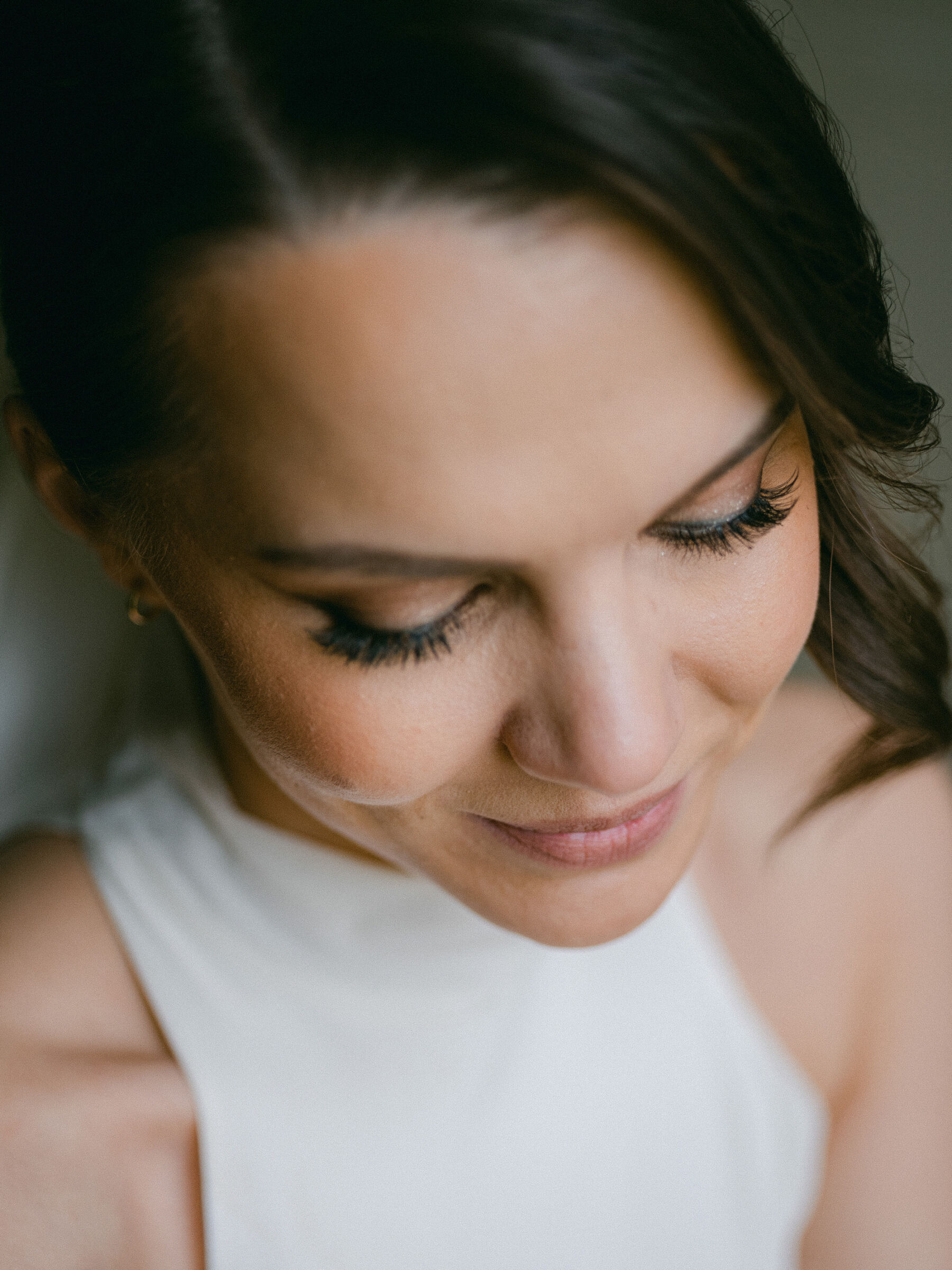 Portrait of a bride looking down to showcase her elegant wedding day makeup.