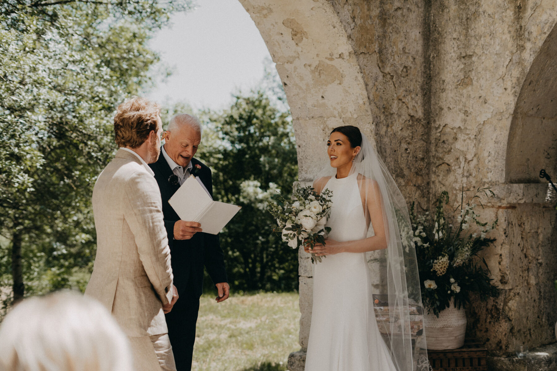 Outdoor wedding at a French chateau. Bride wears a halterneck silk wedding dress.