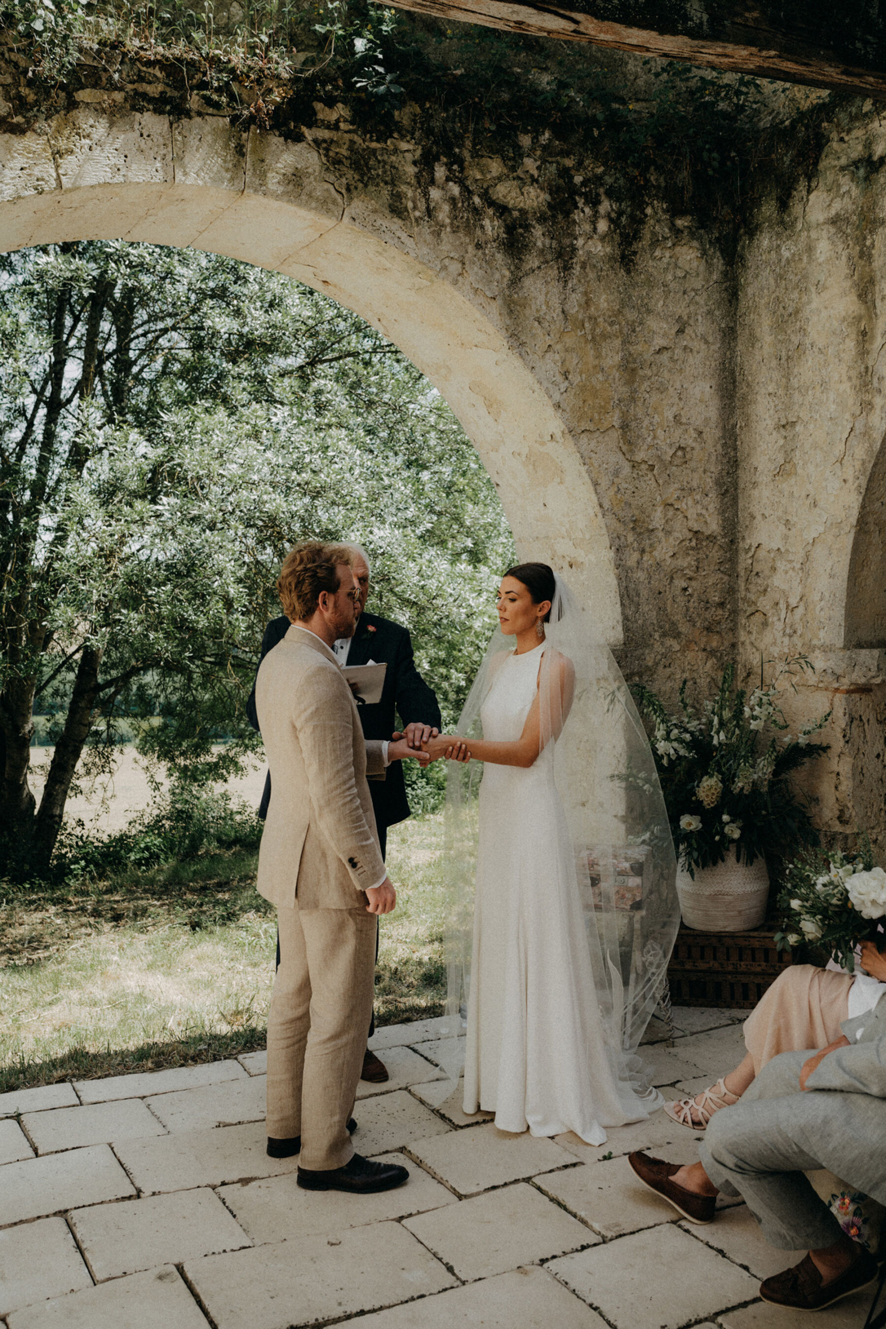 Outdoor wedding at a French chateau. Bride wears a halterneck silk wedding dress.
