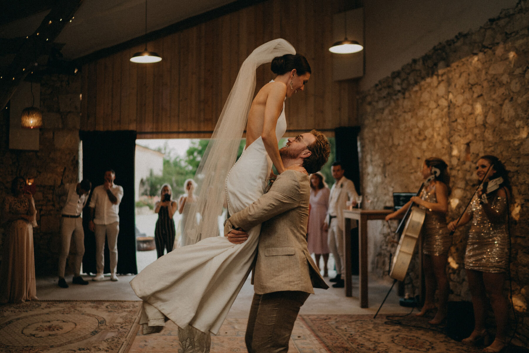 Groom lifting his bride in a halterneck wedding dress on the dancefloor.