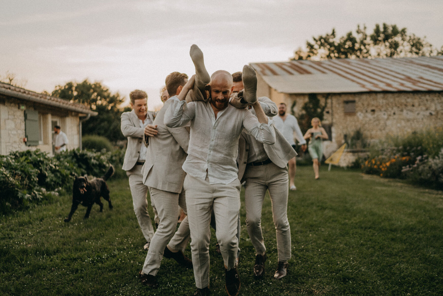 Groomsmen throwing the groom into a swimming pool. 