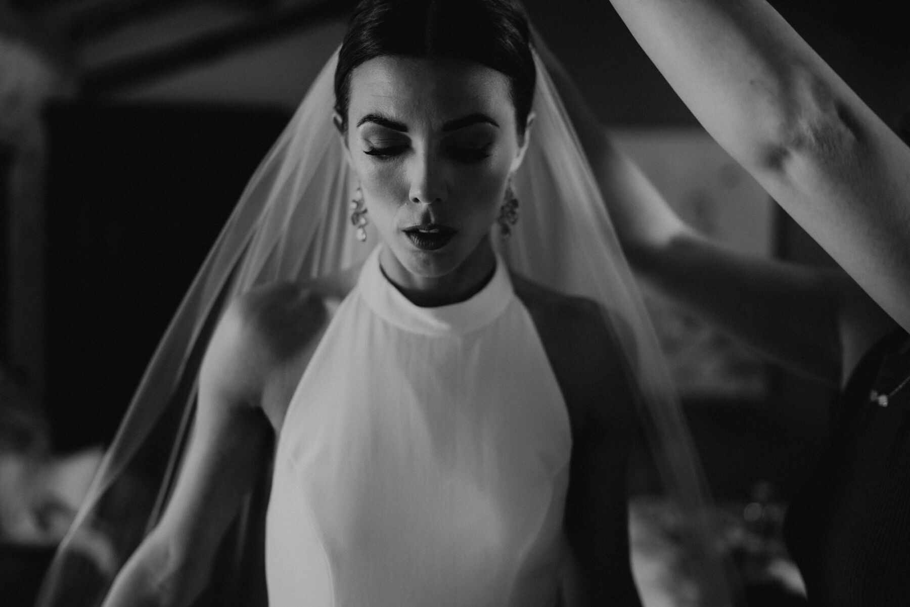 Bride in a halterneck wedding dress and low bun having her veil applied.