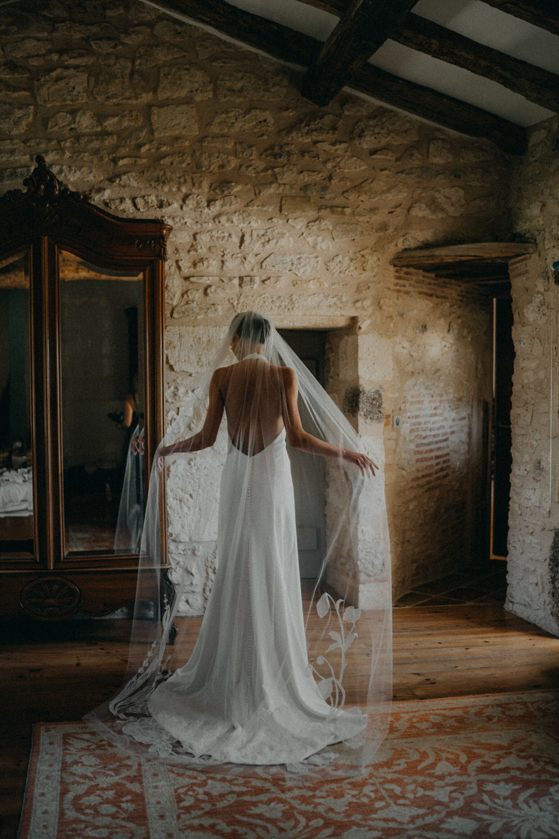 Bride in a sensuous, backless halterneck wedding dress and embroidered veil.