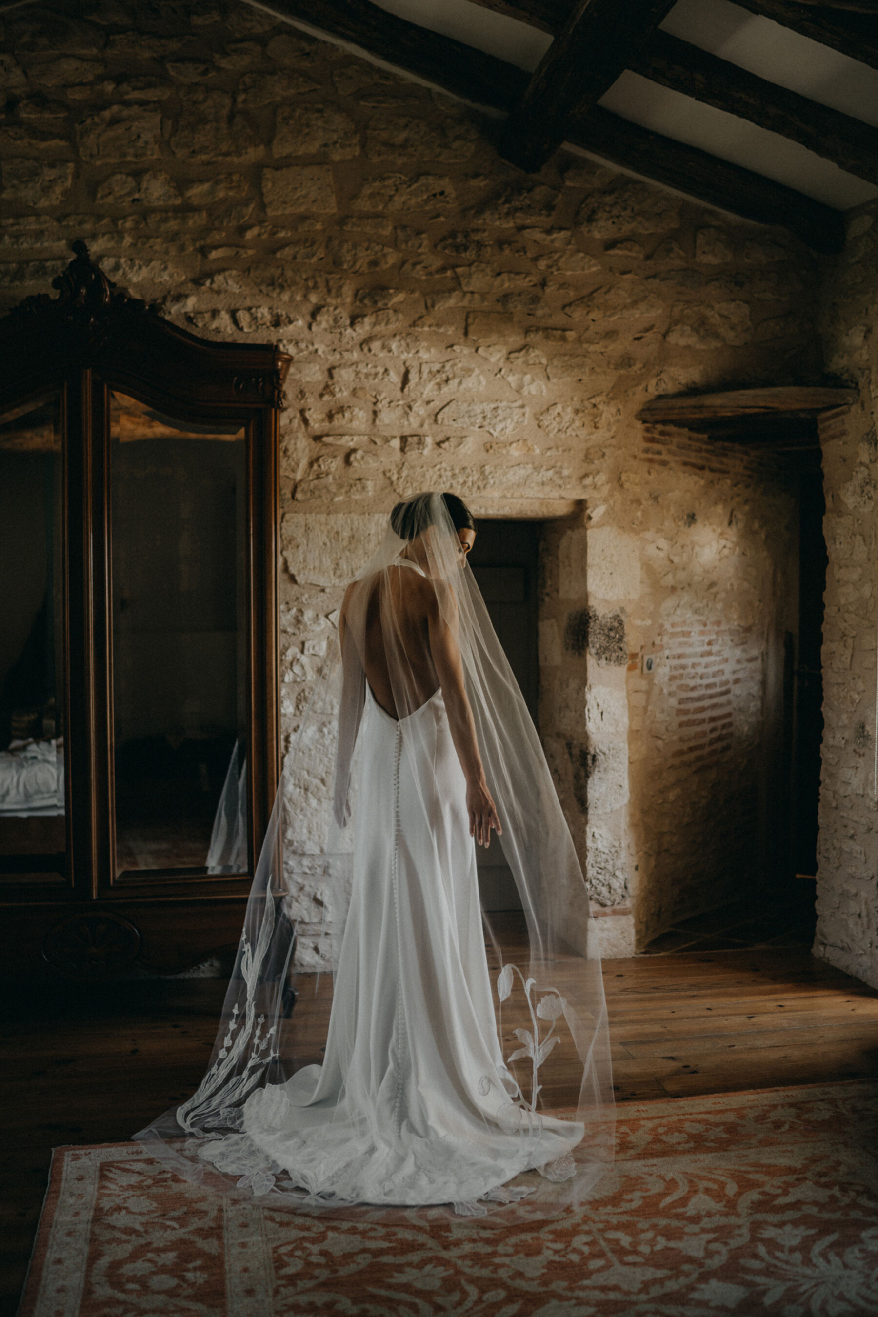 Bride in a sensuous, backless halterneck wedding dress and embroidered veil.