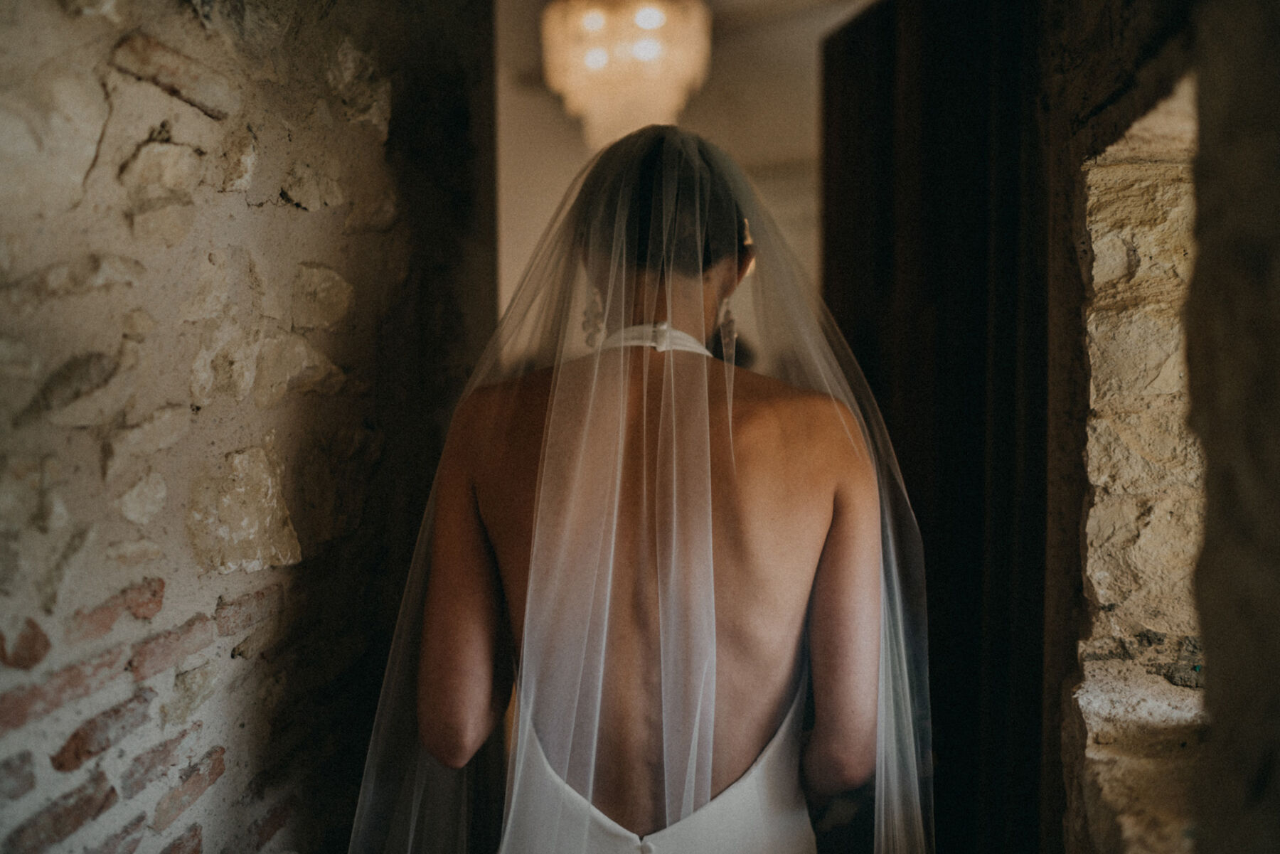Bride in a sensuous, backless halterneck wedding dress and embroidered veil.