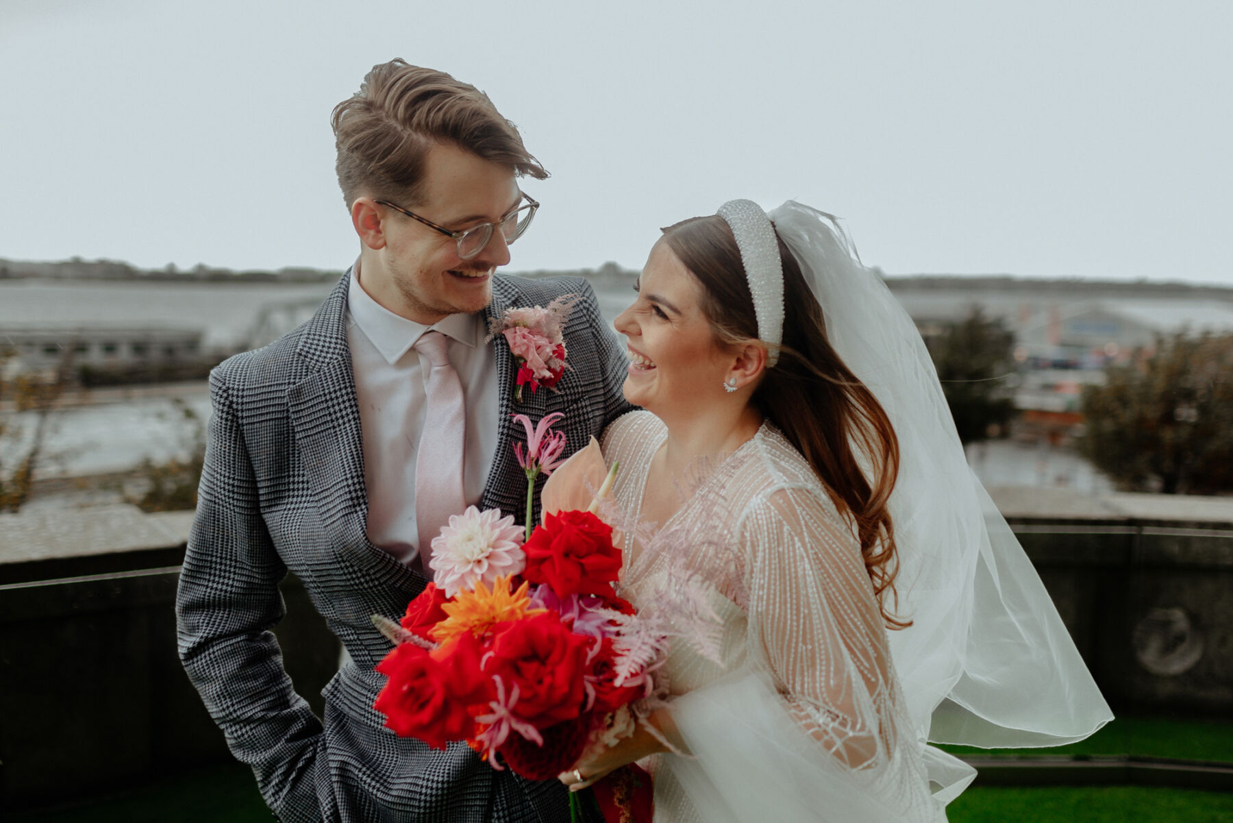 Bride with perl headband, sequin wedding dress and carrying a bright and colourful wedding bouquet.