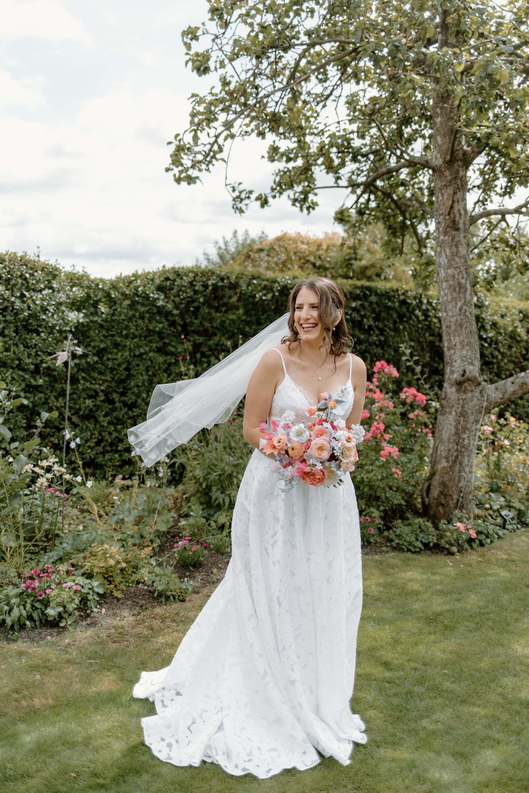 Livia in a Truvelle Bridal Gown for her Durham Castle Wedding With an Outdoor Summer Garden Ceremony 8 Bride wearing a Truvelle Wedding Dress, carrying a pastel colour summer wedding bouquet.
