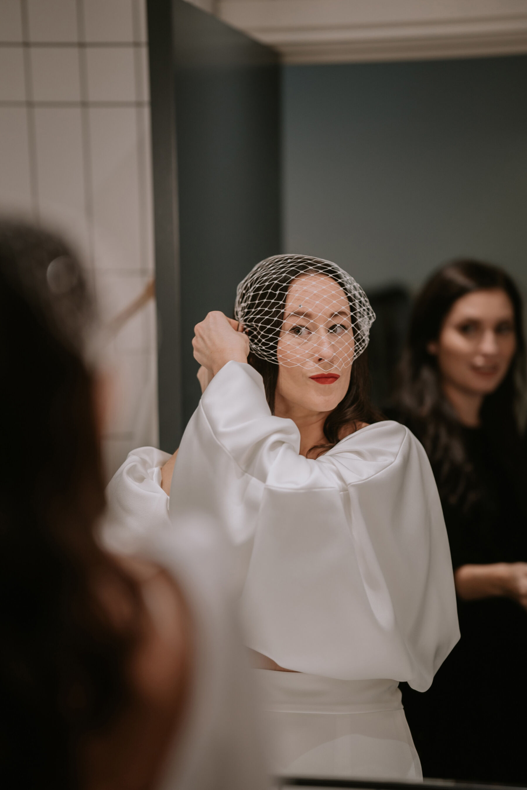 Bride with red lipstick attaching a birdcage veil