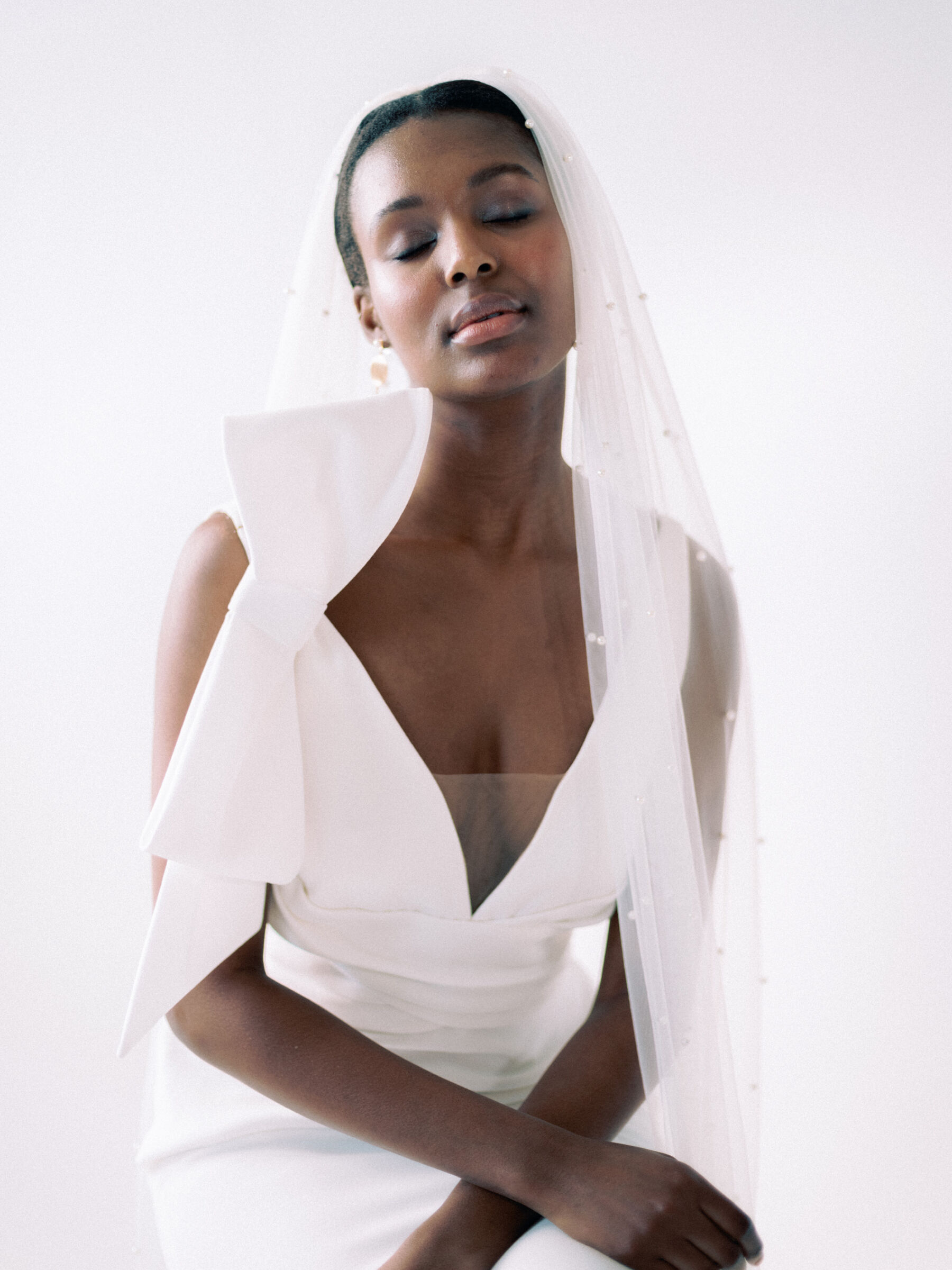 Black bride wearing pearl wedding veil & modern wedding dress with large bow 