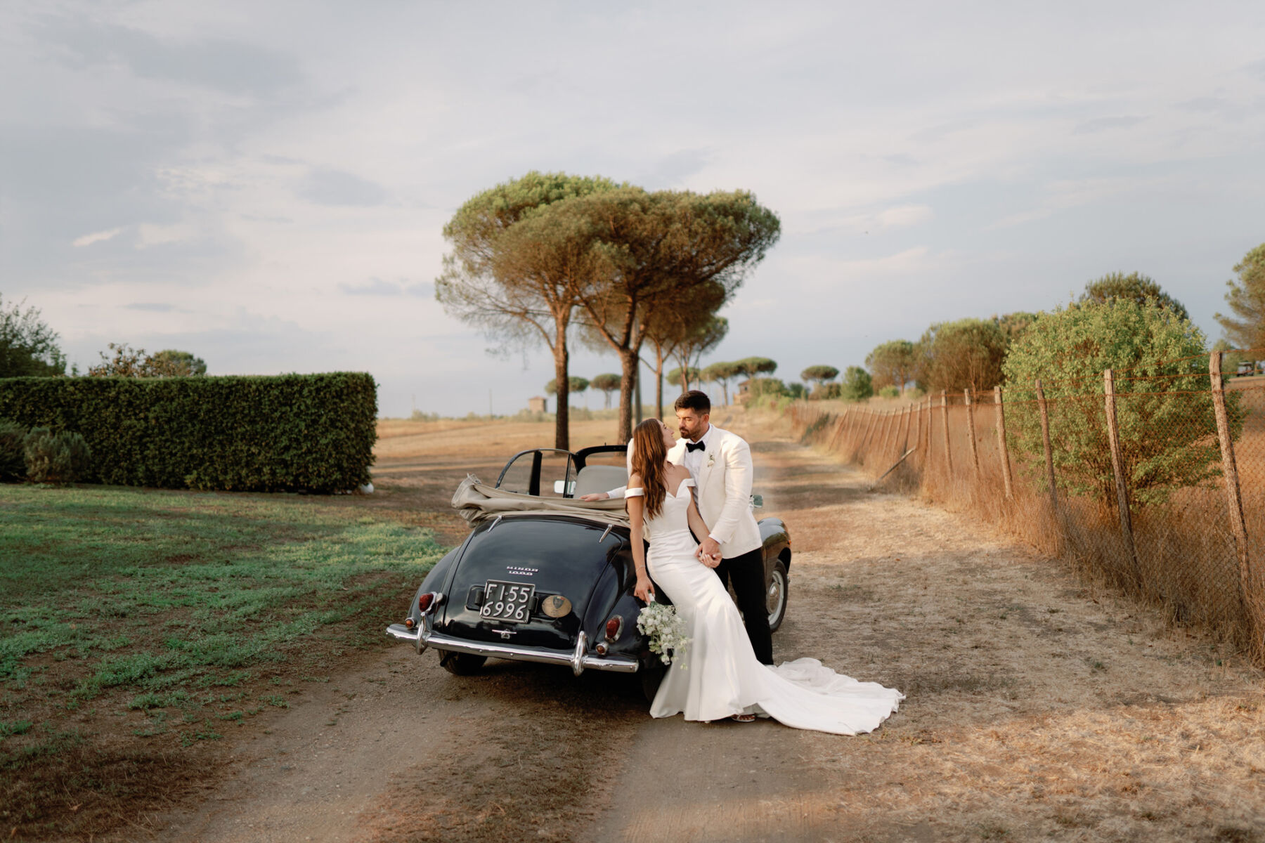 Bride and groom leaning next to an open top vintage car in Rome Italy