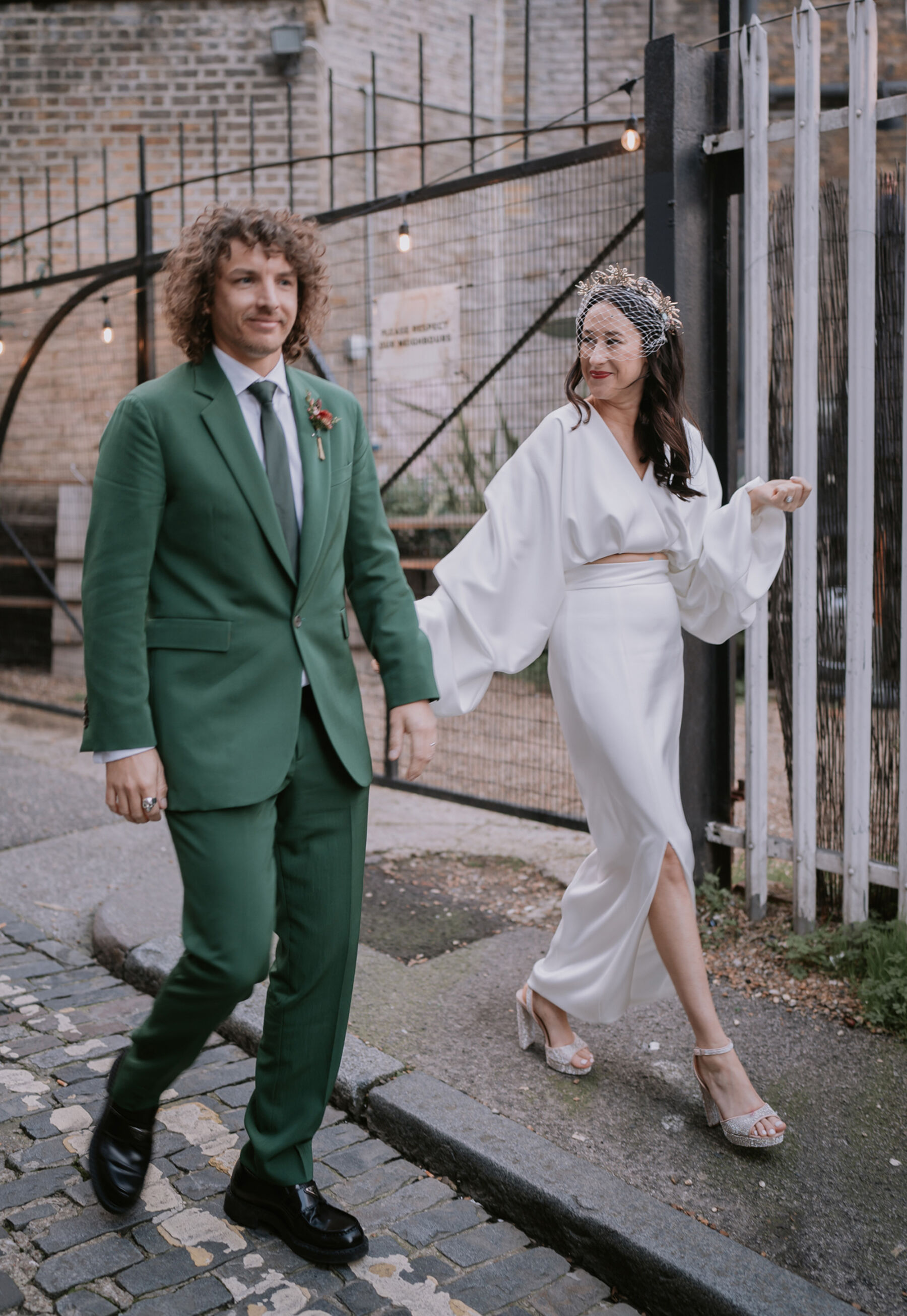 Bride in modern and ultrastylish Bon Bride wedding dress. Groom in Paul Smith green suit.