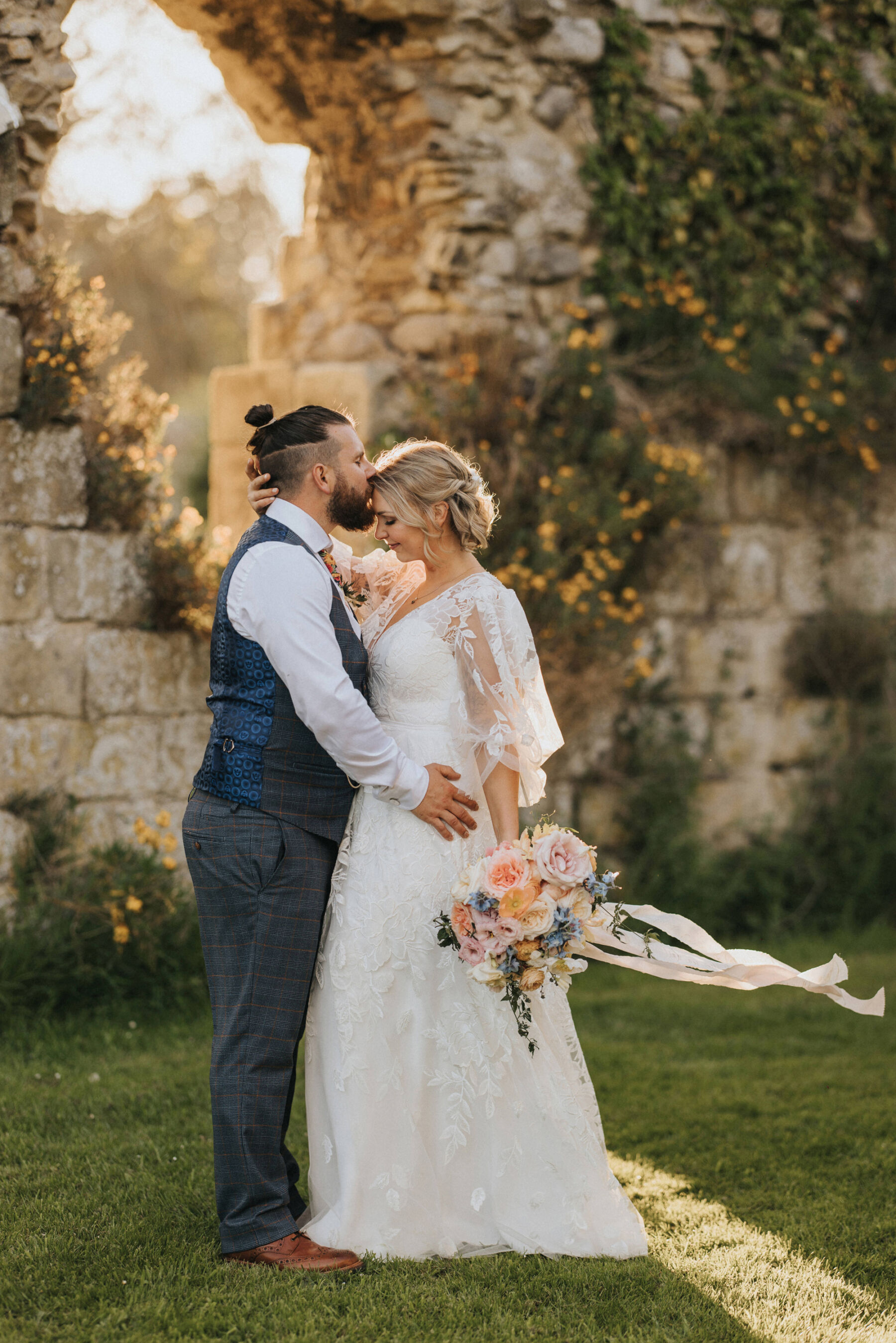 Bride wearing a Savin London wedding dress and carrying a pastel colour large wedding bouquet with trailing silk ribbons