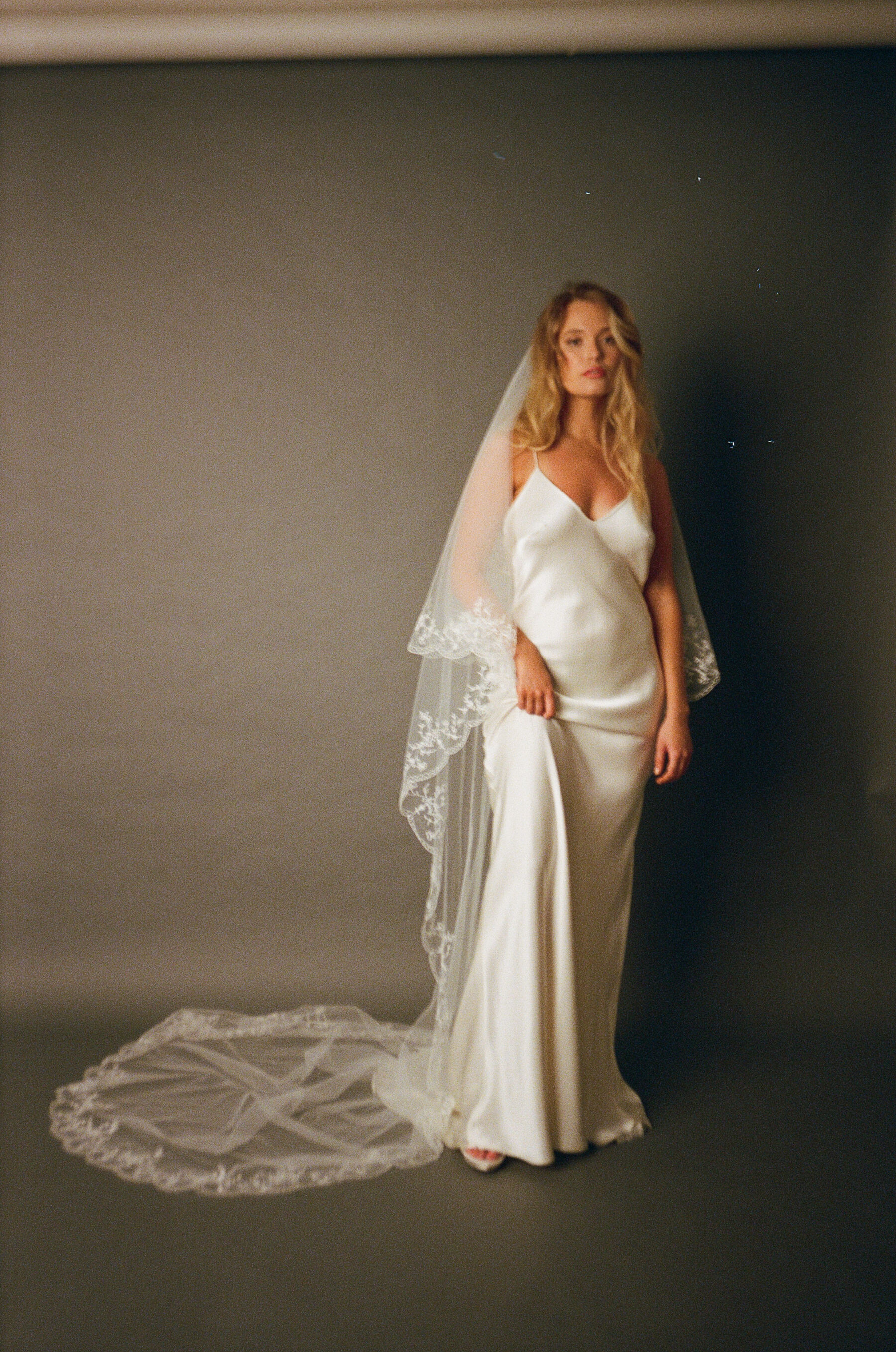 Analogue photograph of model bride wearing a Kate Beaumont silk slip dress with a floor length lace edged veil.