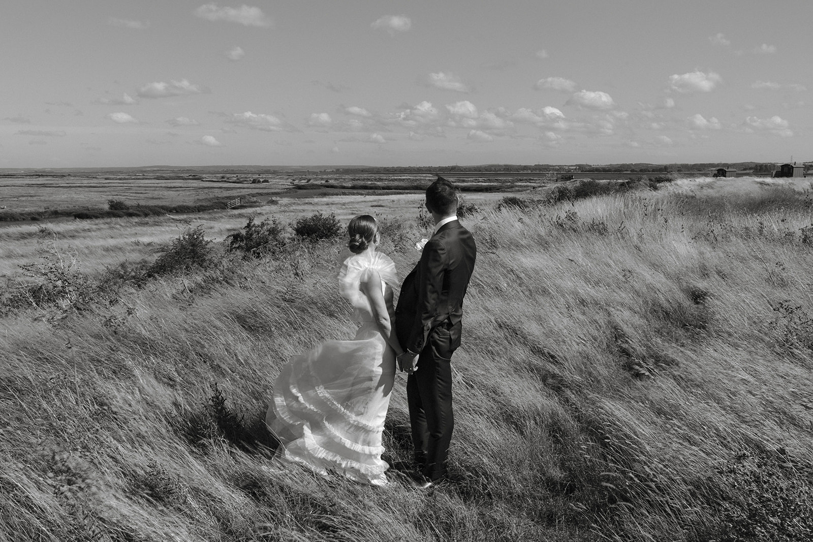 Beautiful modern black and white photograph of bride and groom standing in a field